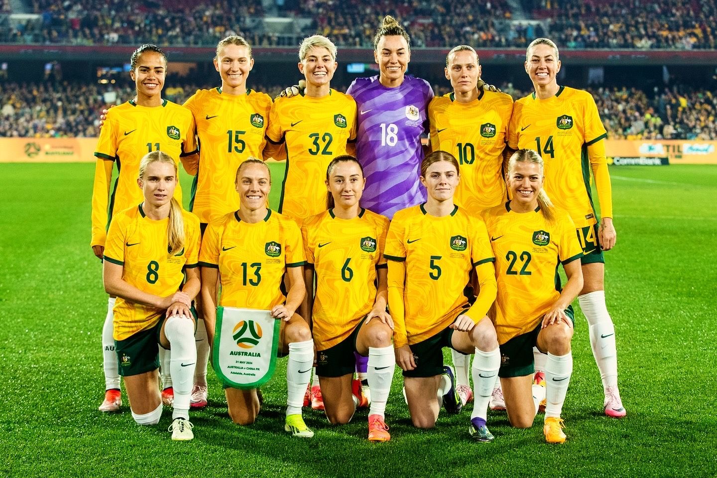 Soccer team poses for official group photo on field before match.