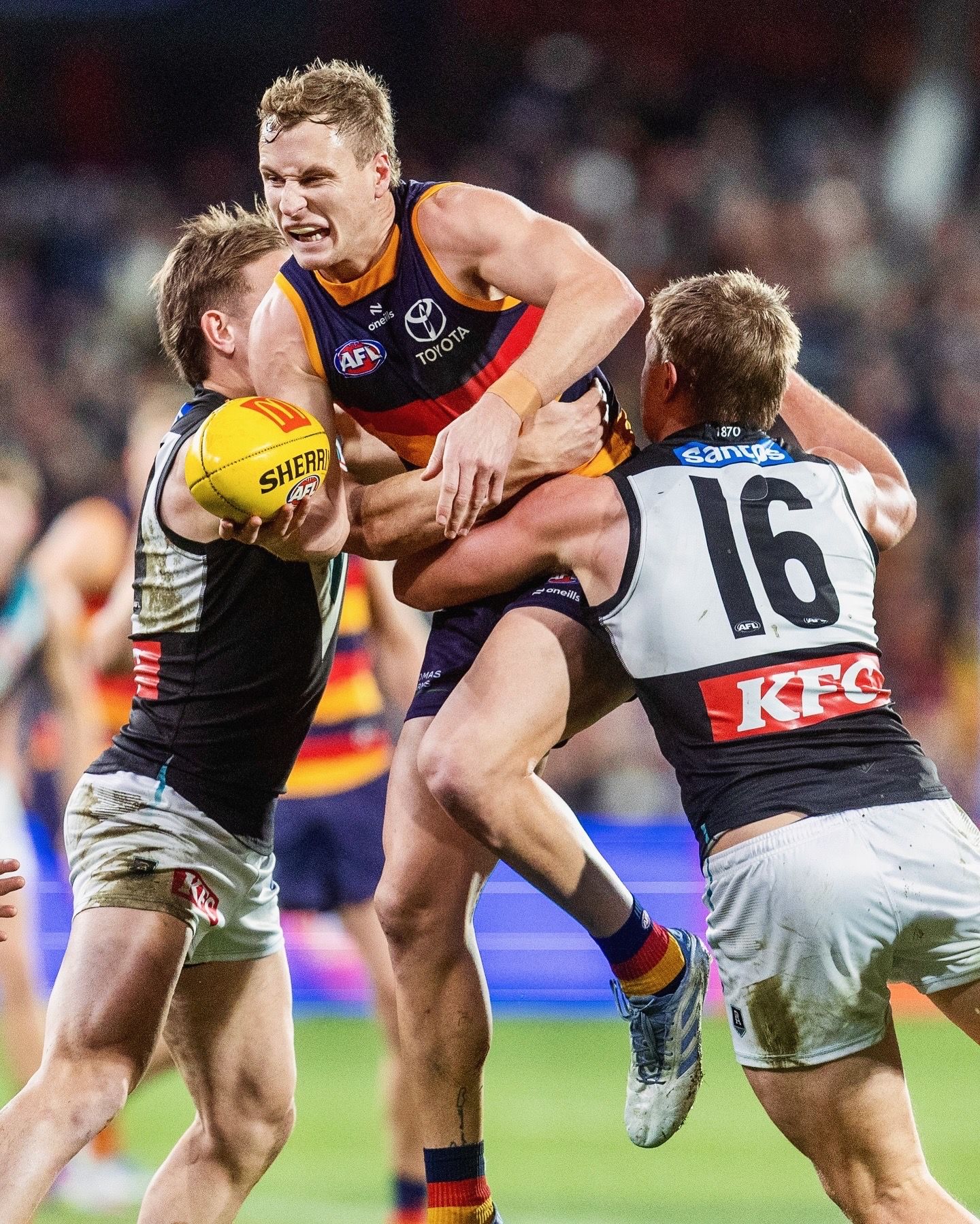 AFL players battle for possession of the ball in intense marking contest during match.