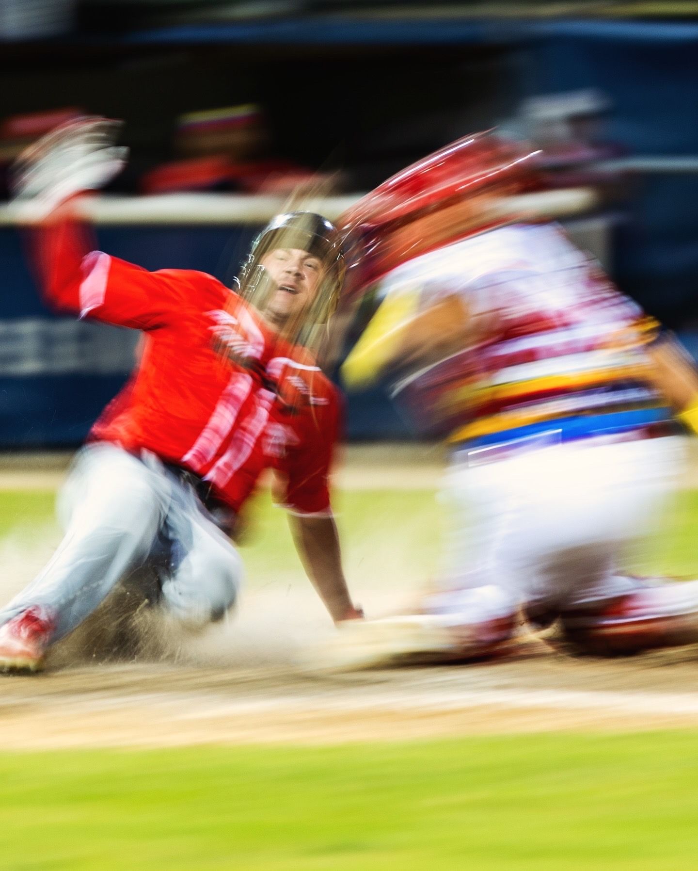Motion blur of athletes in red uniforms running across a sports field during a game.