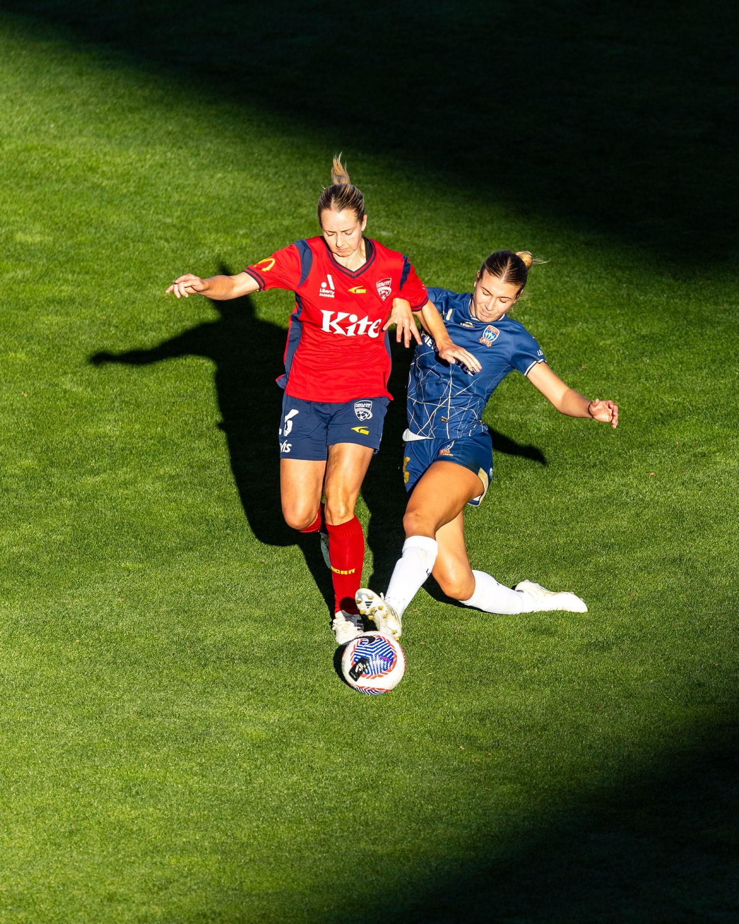 Athletes practicing stretching exercises on a sunlit grass field.