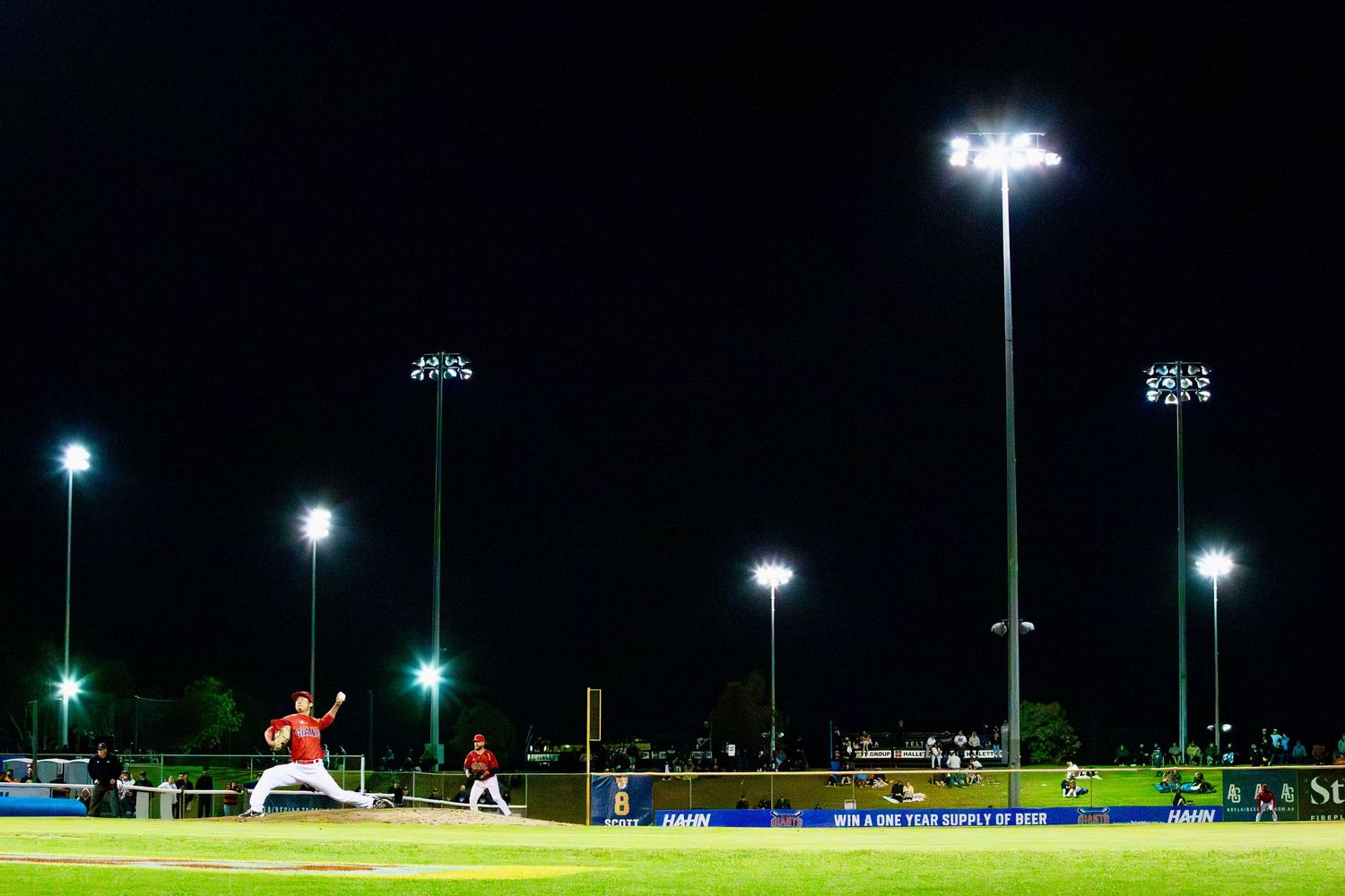 Night view of baseball field illuminated by stadium lights during game.