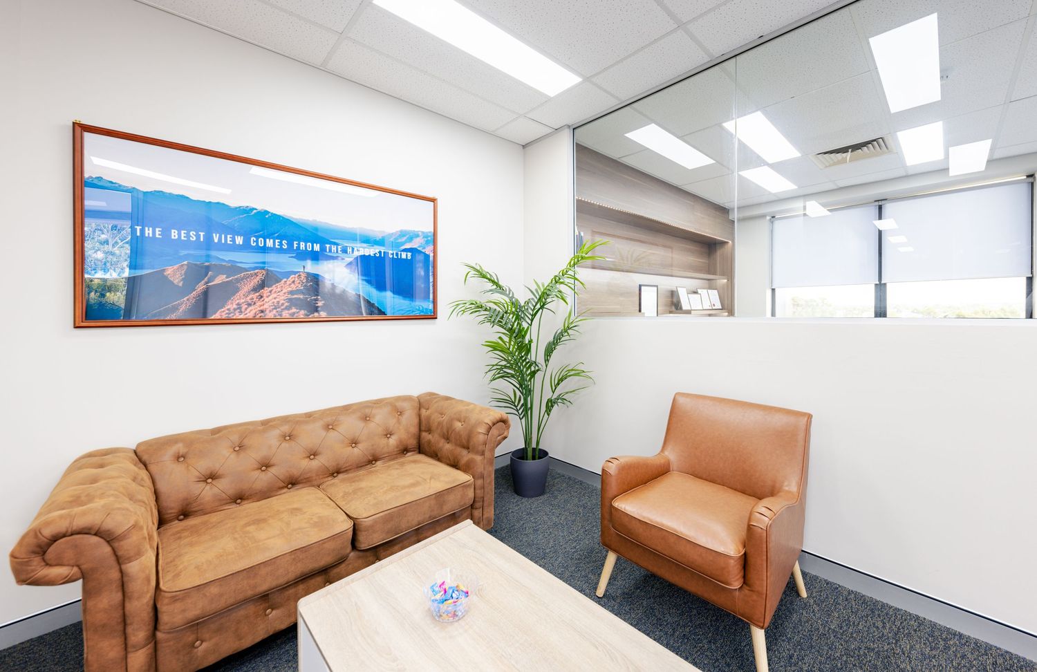 Modern office interior with brown leather furniture and white walls showcasing a panoramic view of multiple seating areas.