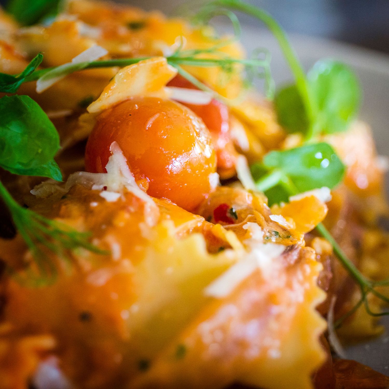 Fresh pasta dish garnished with herbs and colorful ingredients in macro shot.