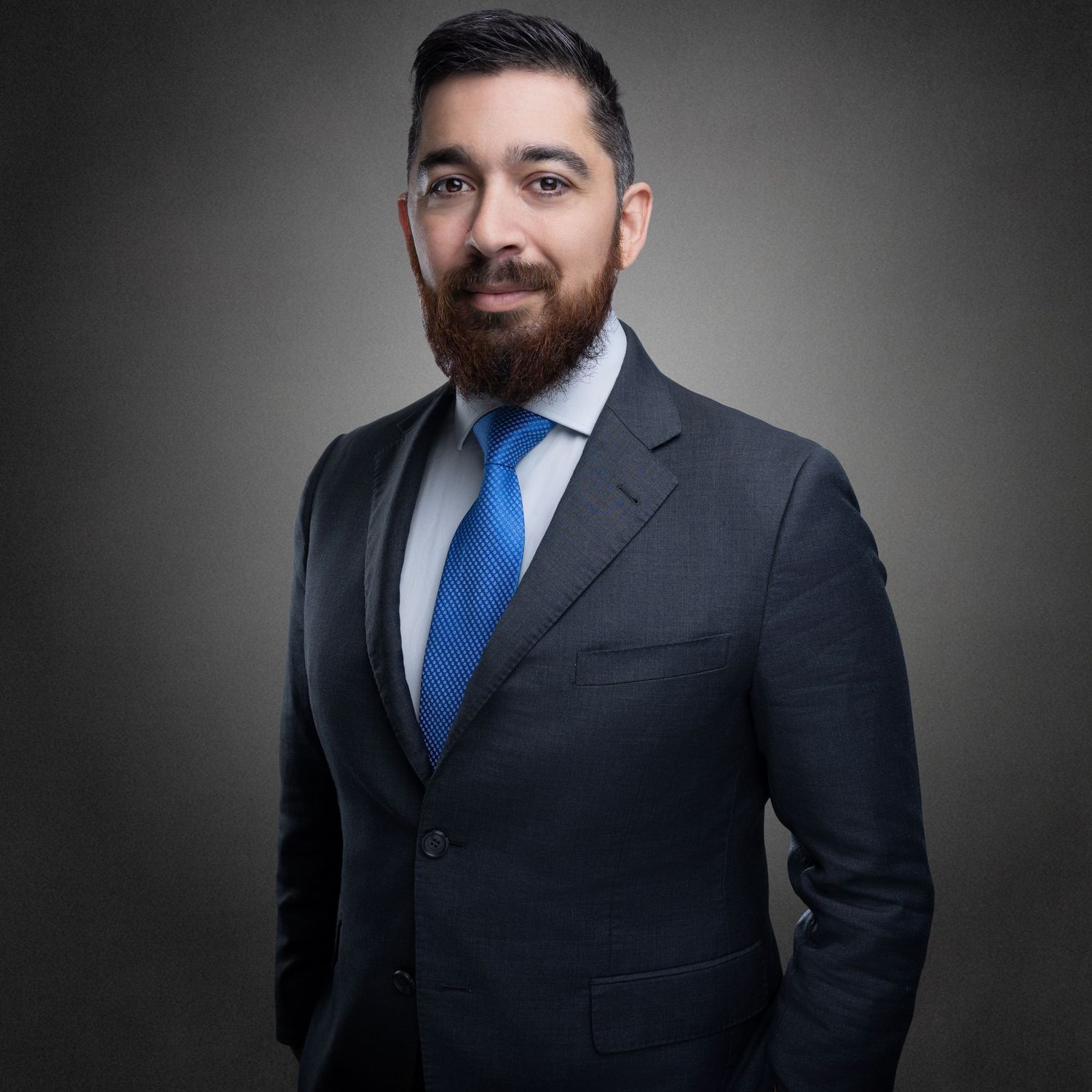 Business professionals in dark suits against a gray studio background.
