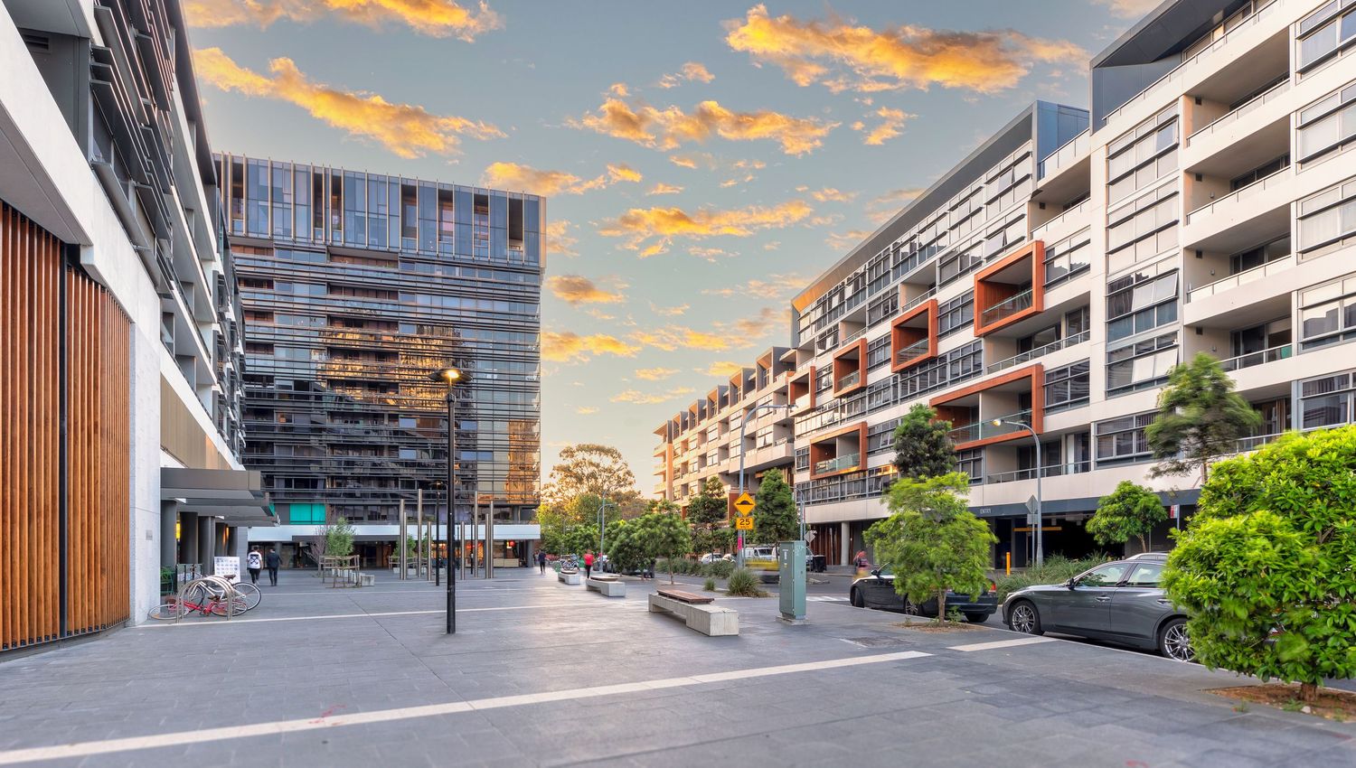 Contemporary apartment complex with long balconies and geometric architecture at sunset with orange clouds.