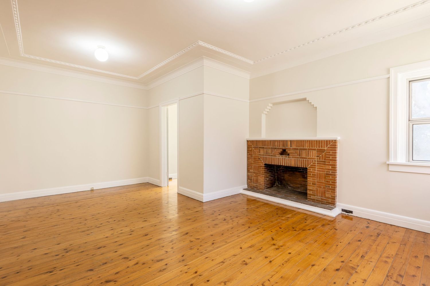 Interior room renovation progress showing hardwood floor installation and white walls in various stages of completion.