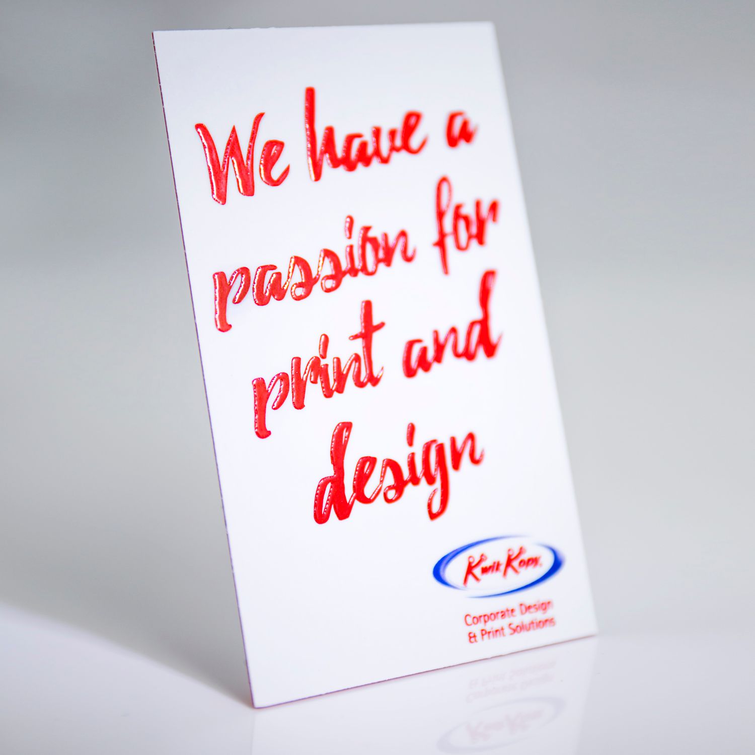 Standing white business card with red handwritten style text about print design passion.