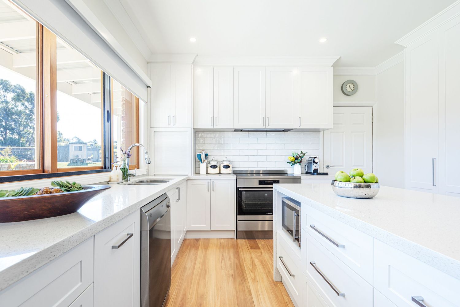 Modern white kitchen with butcher block countertops and sleek cabinet design features abundant natural lighting.