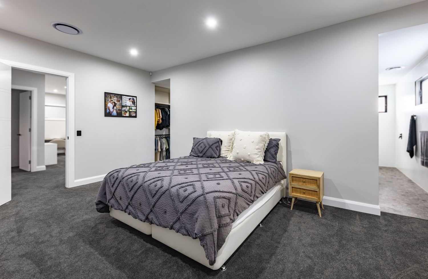 A 360-degree panoramic view of a modern basement bedroom with gray carpet and white walls featuring recessed lighting.