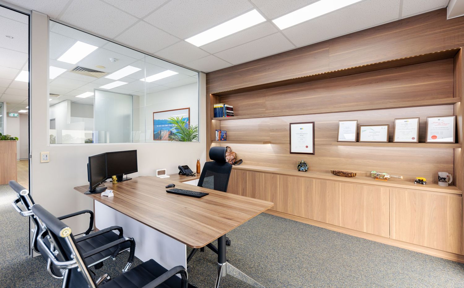 Modern office space with wood paneled walls, ergonomic chairs, and fluorescent lighting in a professional setting.