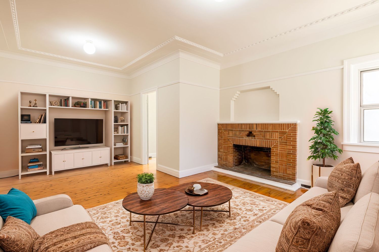 Panoramic view of a modern basement living room with brown furniture, wood floors, and built-in shelving.