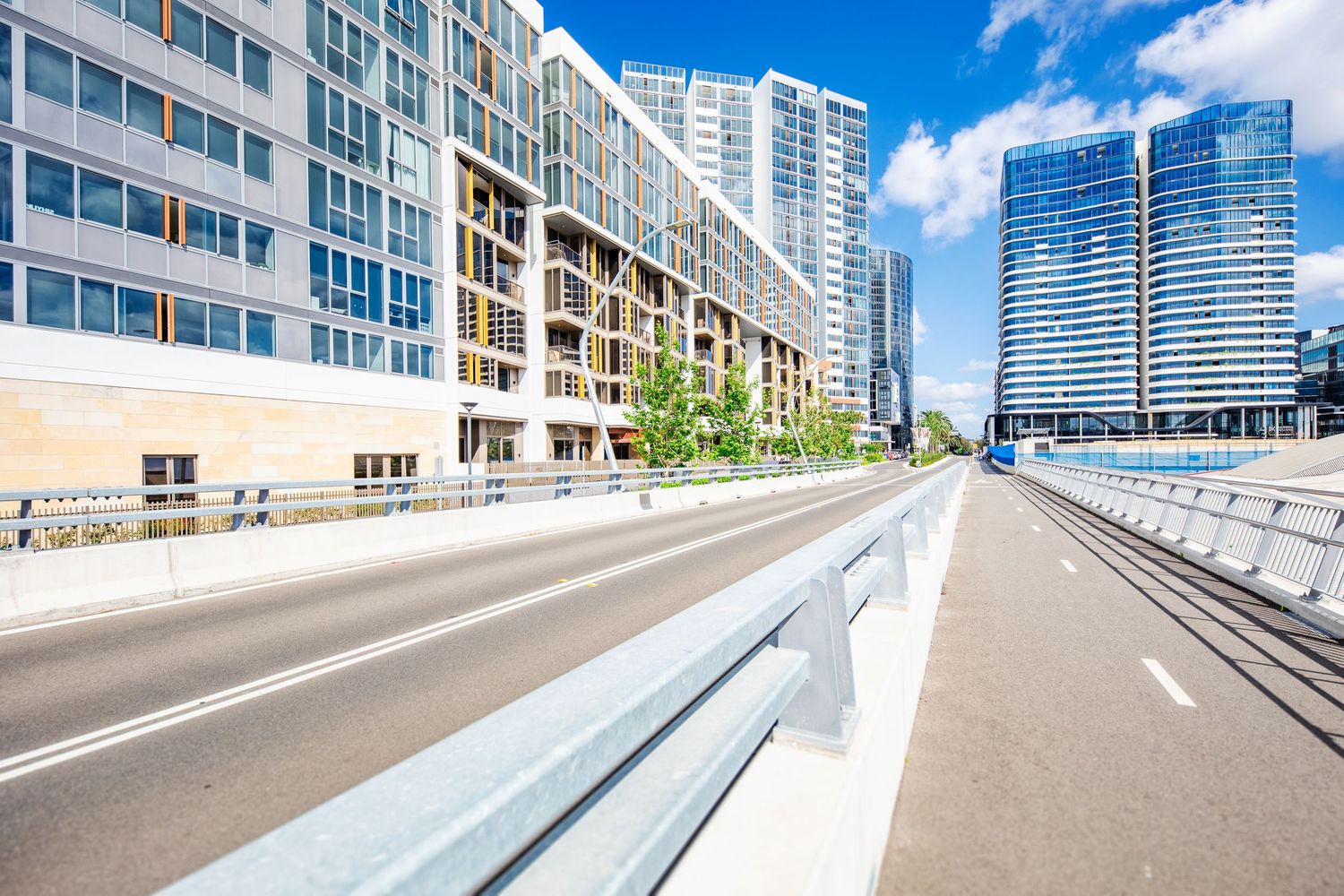 Modern urban street with tall glass buildings and clear blue sky in panoramic view of downtown business district.