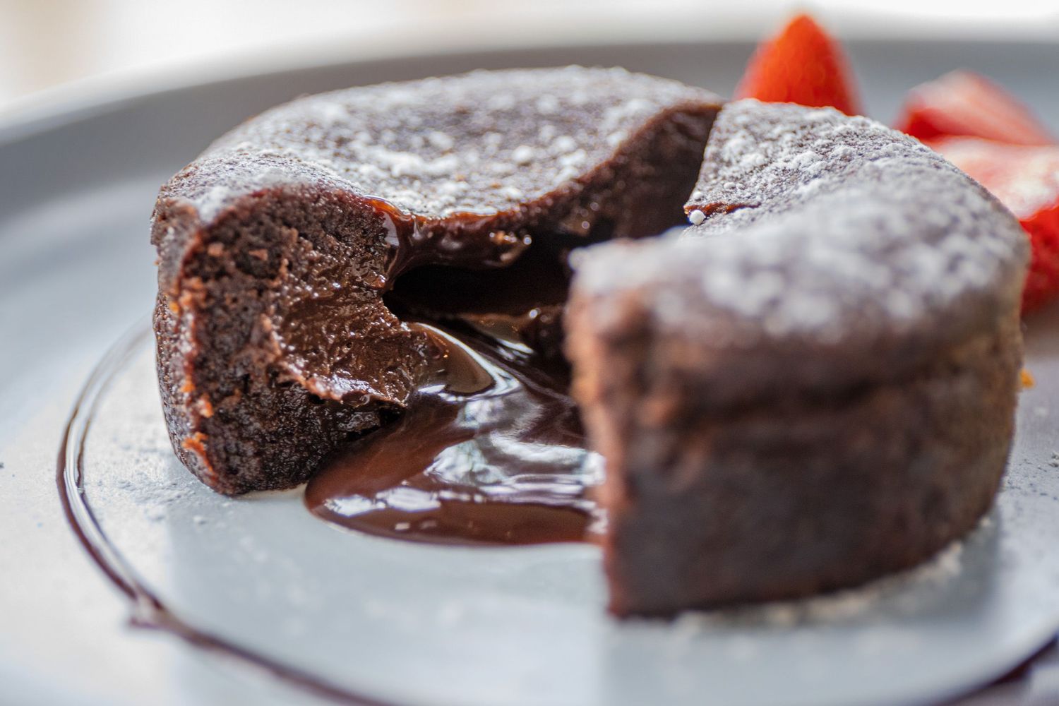 Chocolate lava cake with rich molten center oozing onto white plate.