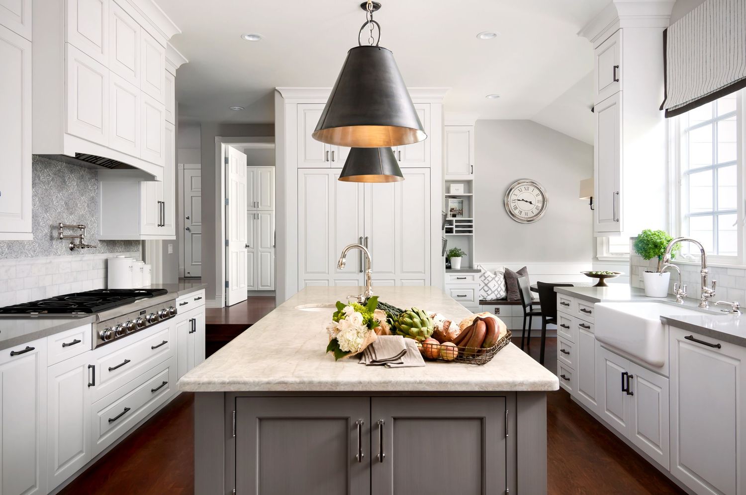 Modern white kitchen design with black pendant lights, marble countertops and stainless steel appliances in open layout.