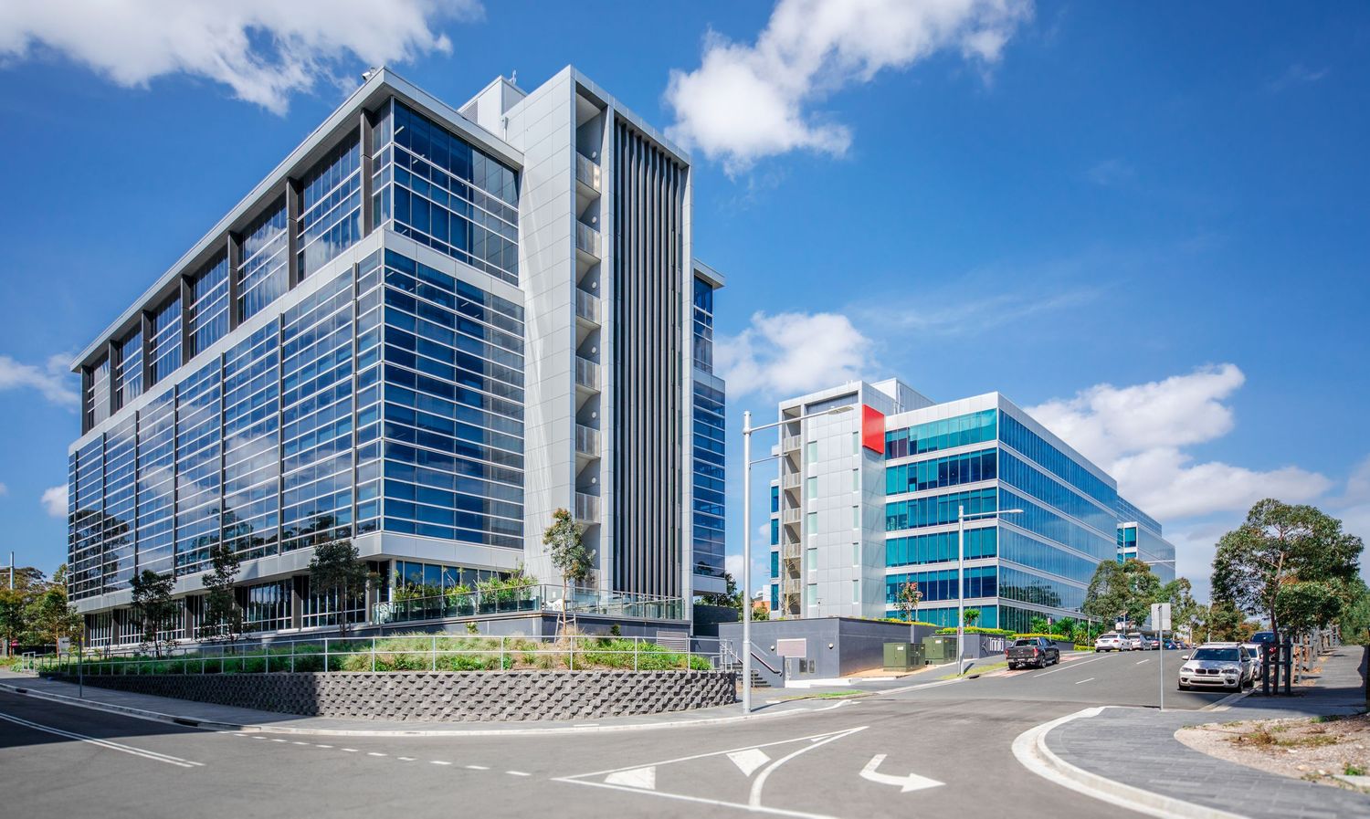 Modern office buildings with glass facades and blue sky reflect sunlight on a bright sunny day.
