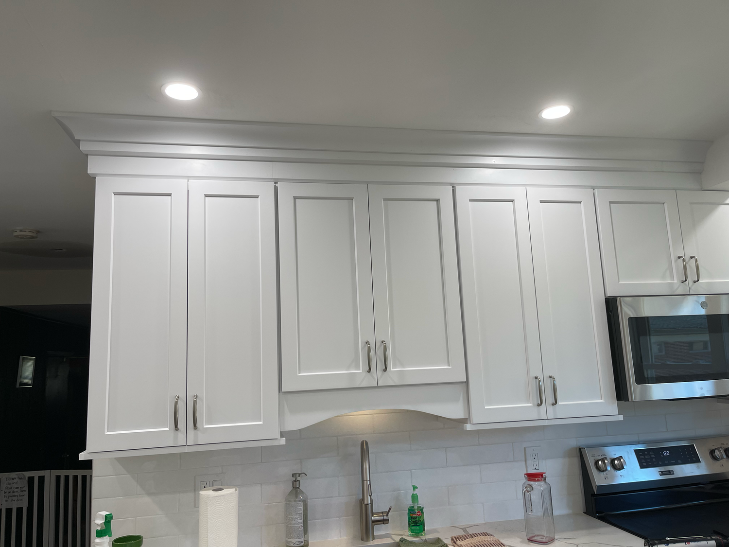 White kitchen cabinets with recessed lighting installed in the ceiling create a bright and modern look.