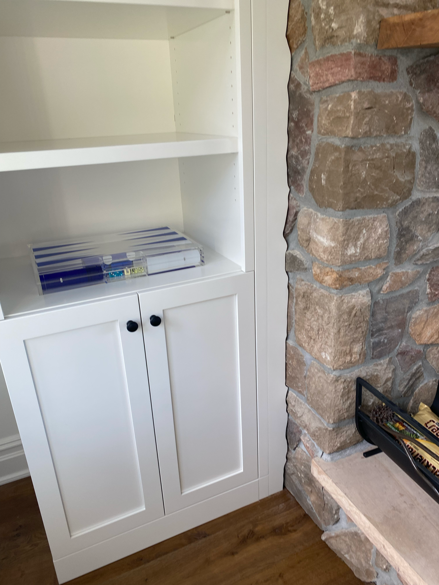 Built-in white cabinet storage with shaker-style doors installed next to exposed brick chimney wall.