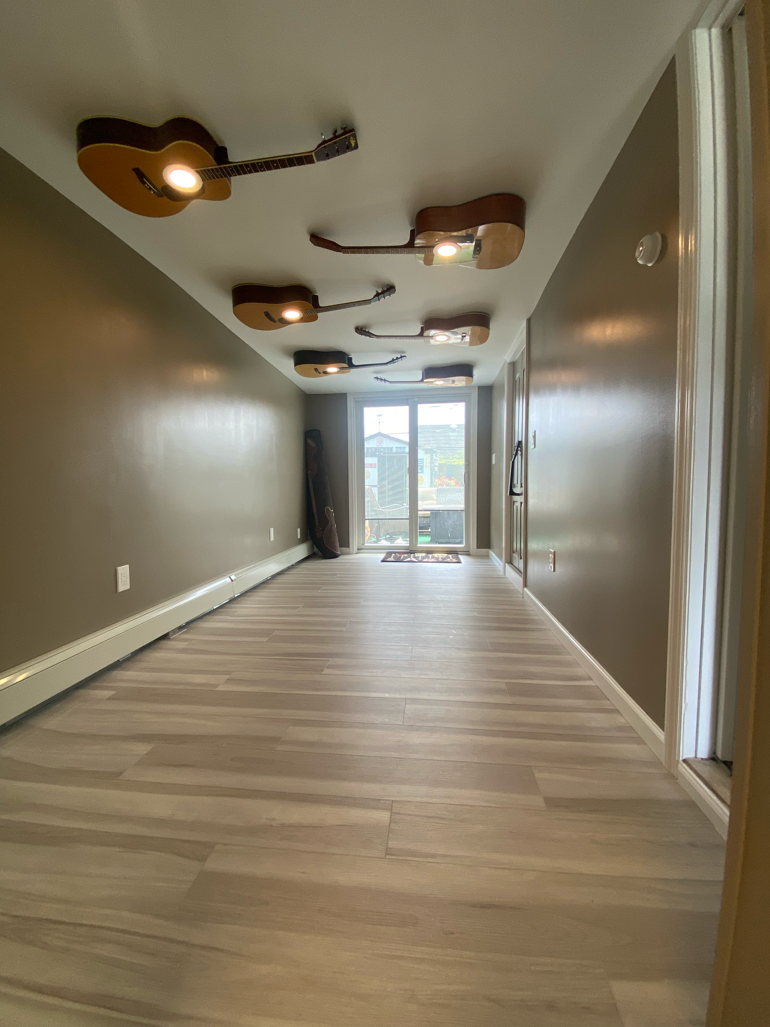 Long hallway with modern wood-look flooring and ceiling-mounted track lighting showcases contemporary interior design.
