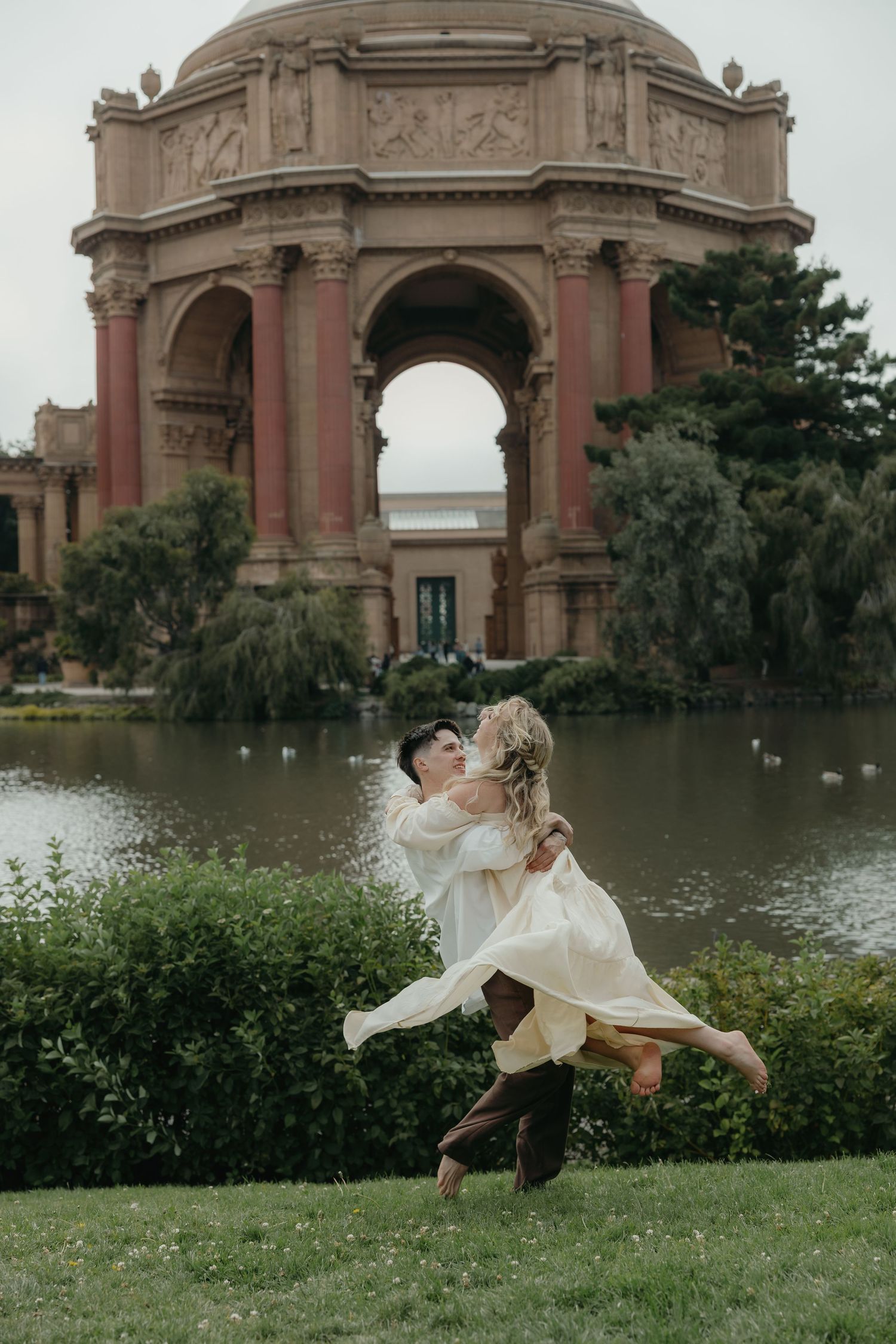 Couple sharing romantic moment, groom lifting bride in front of Palace of Fine Arts rotunda in San Francisco.