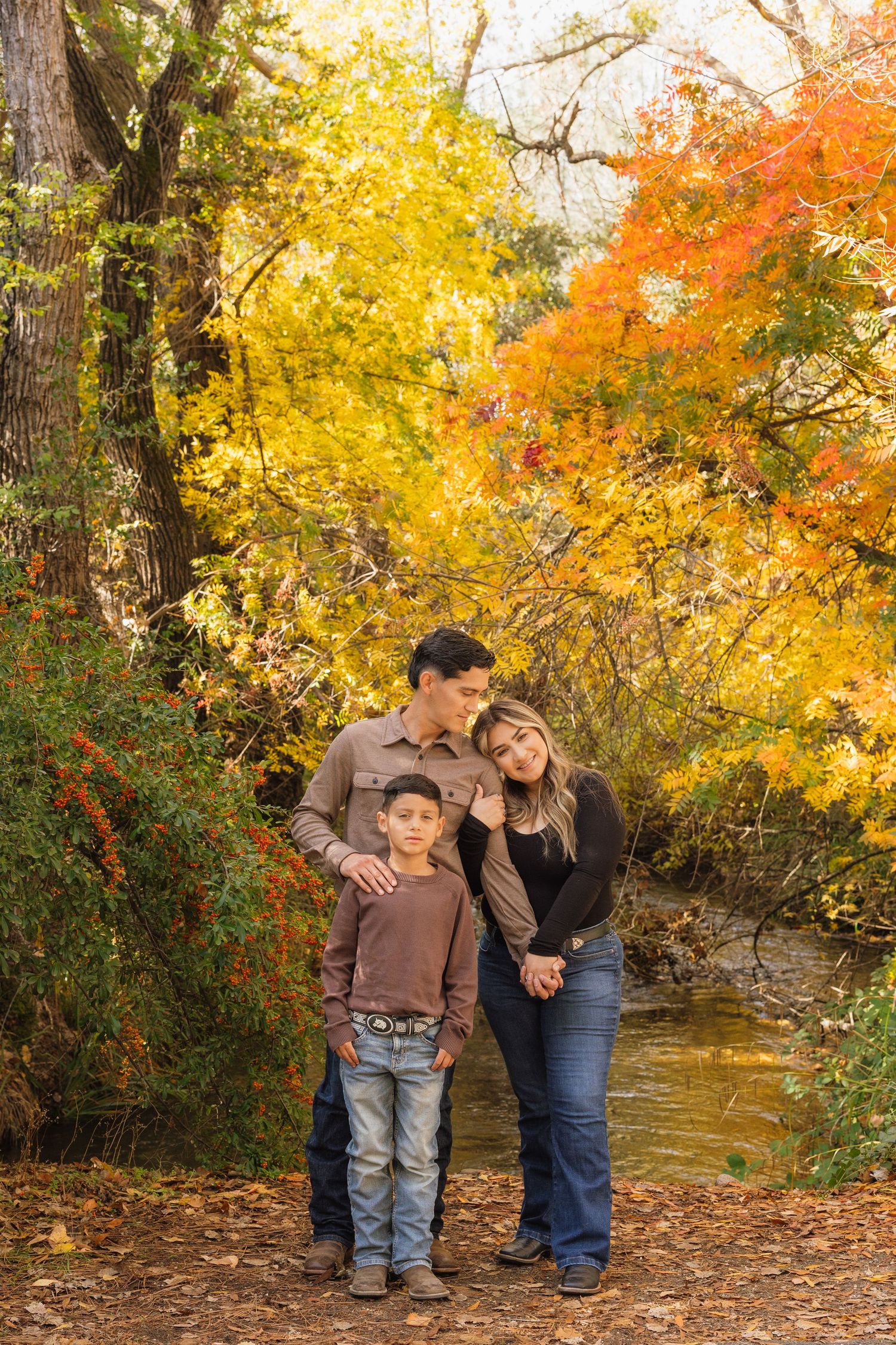 A fall photoshoot with vibrant autumn foliage and a creek in the background.