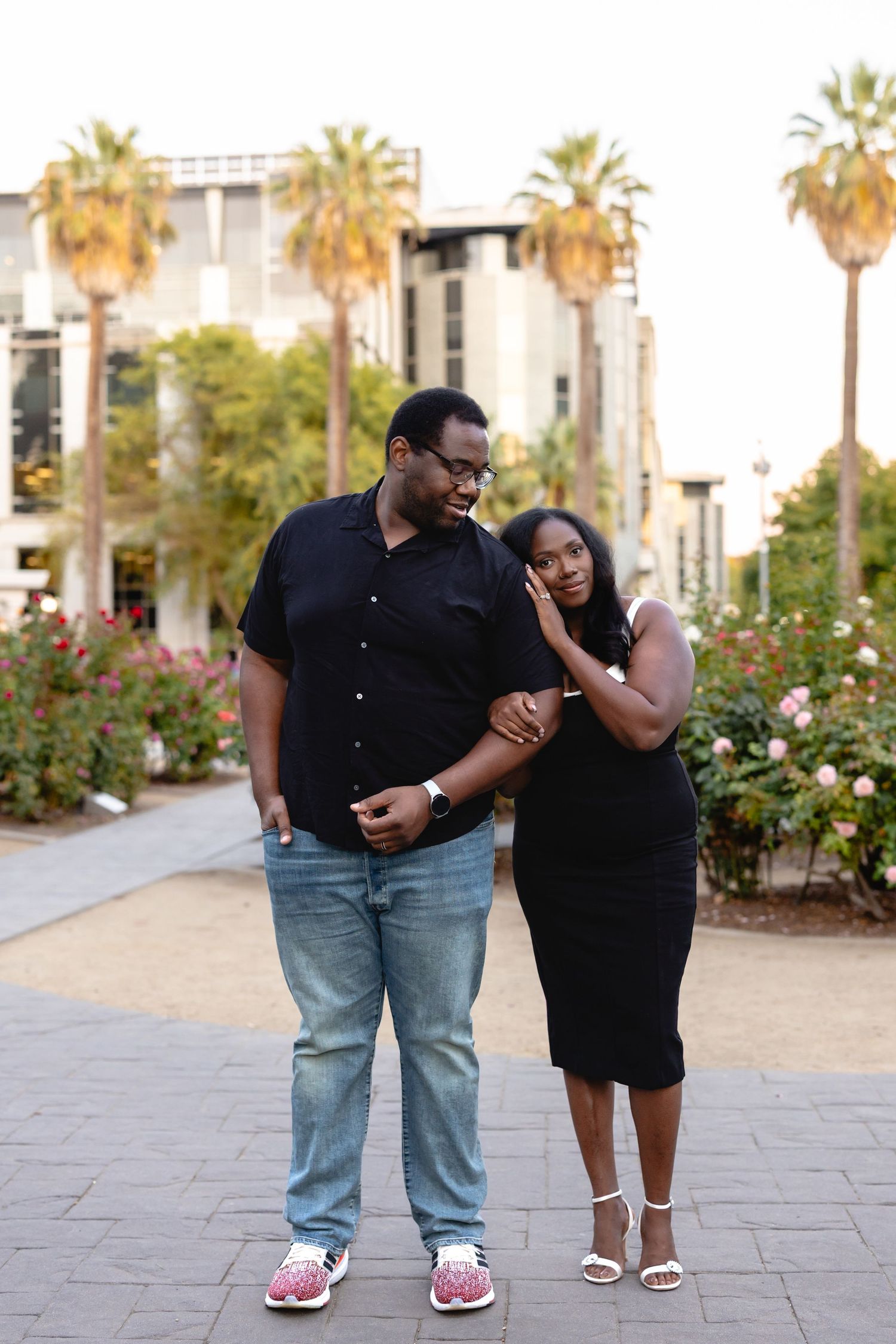 A couple sharing a playful moment on a palm tree-lined walkway.