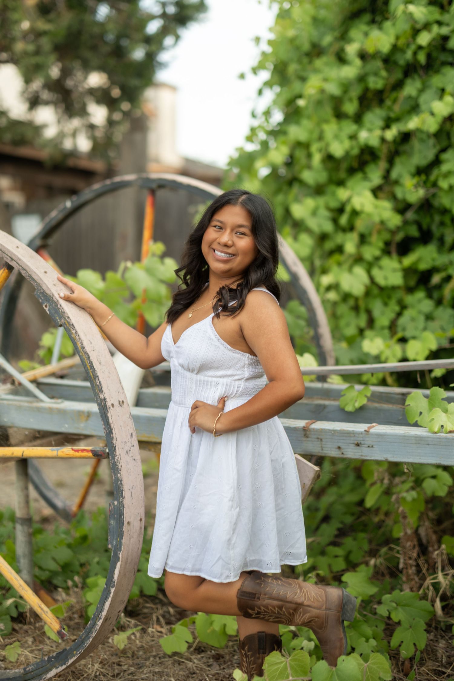 A summer portrait session with a white dress against vintage wooden farm equipment.