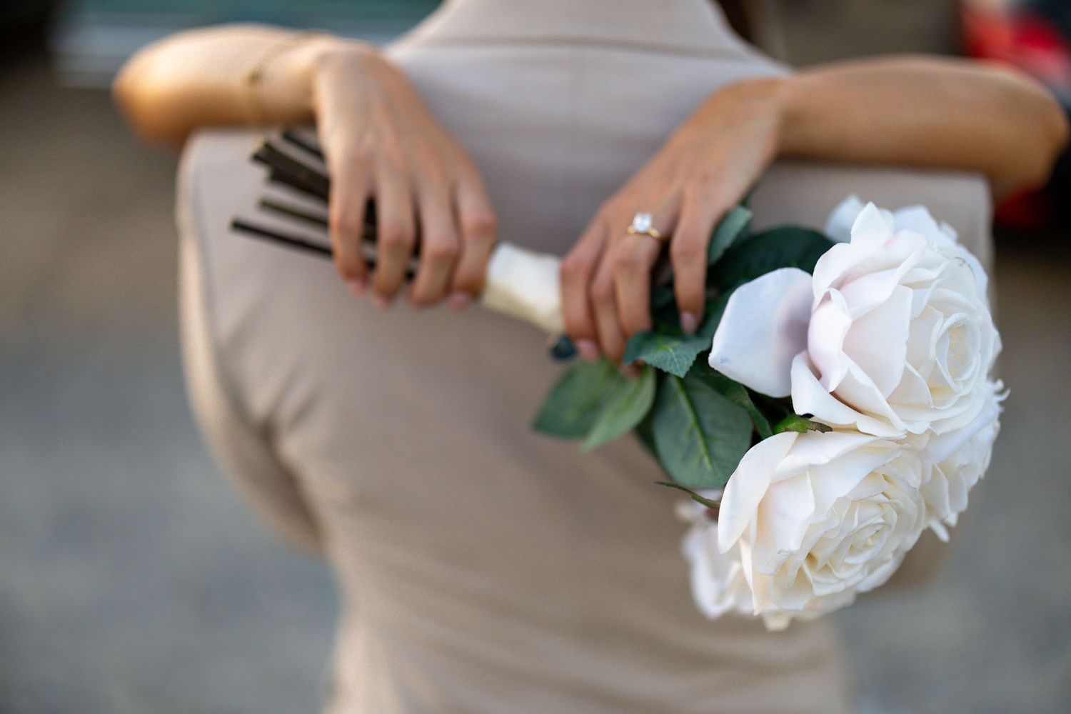 Close-up detail of a white rose being held against a light background.
