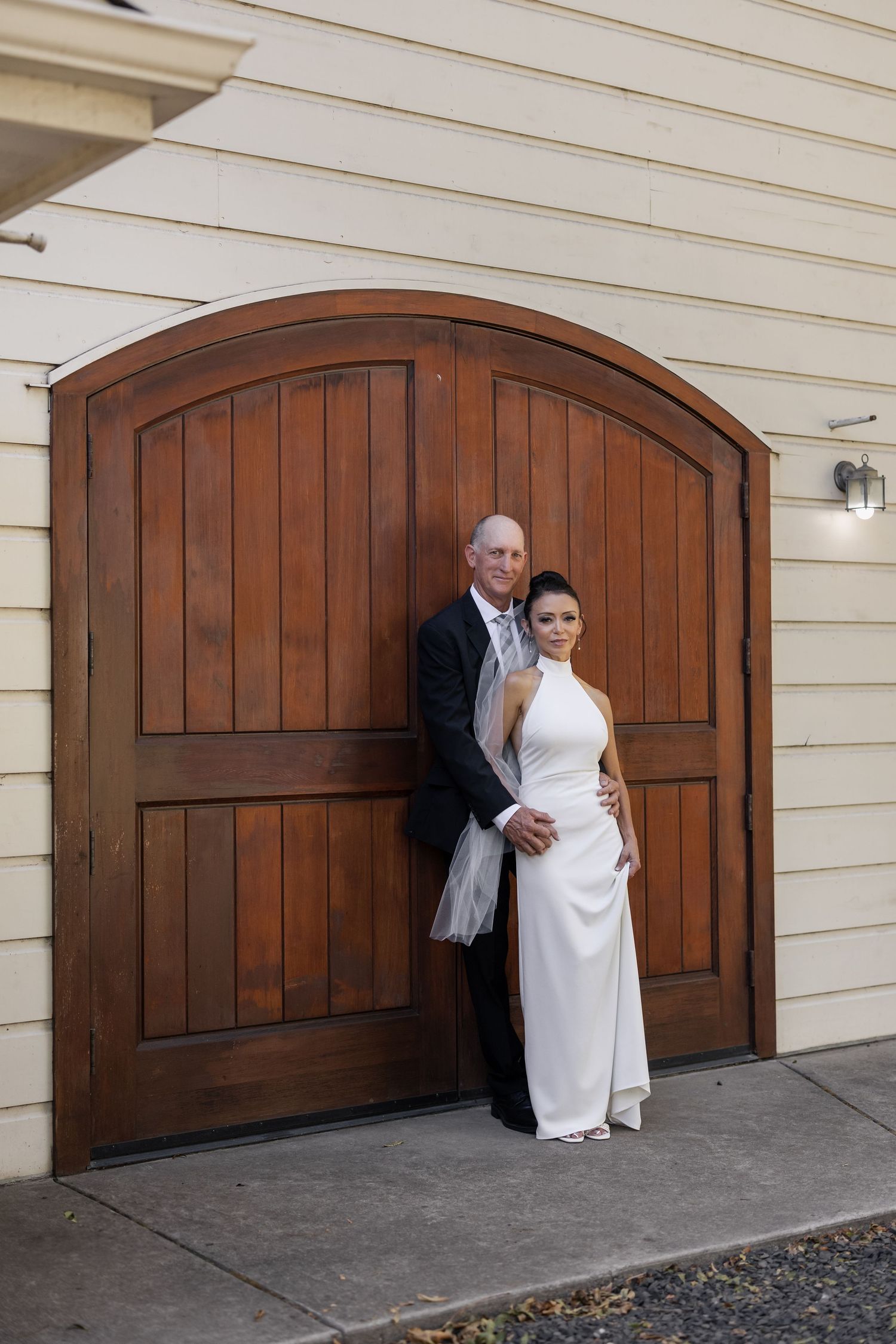 Playful wedding photo sequence showing couple interacting by wooden garage doors.