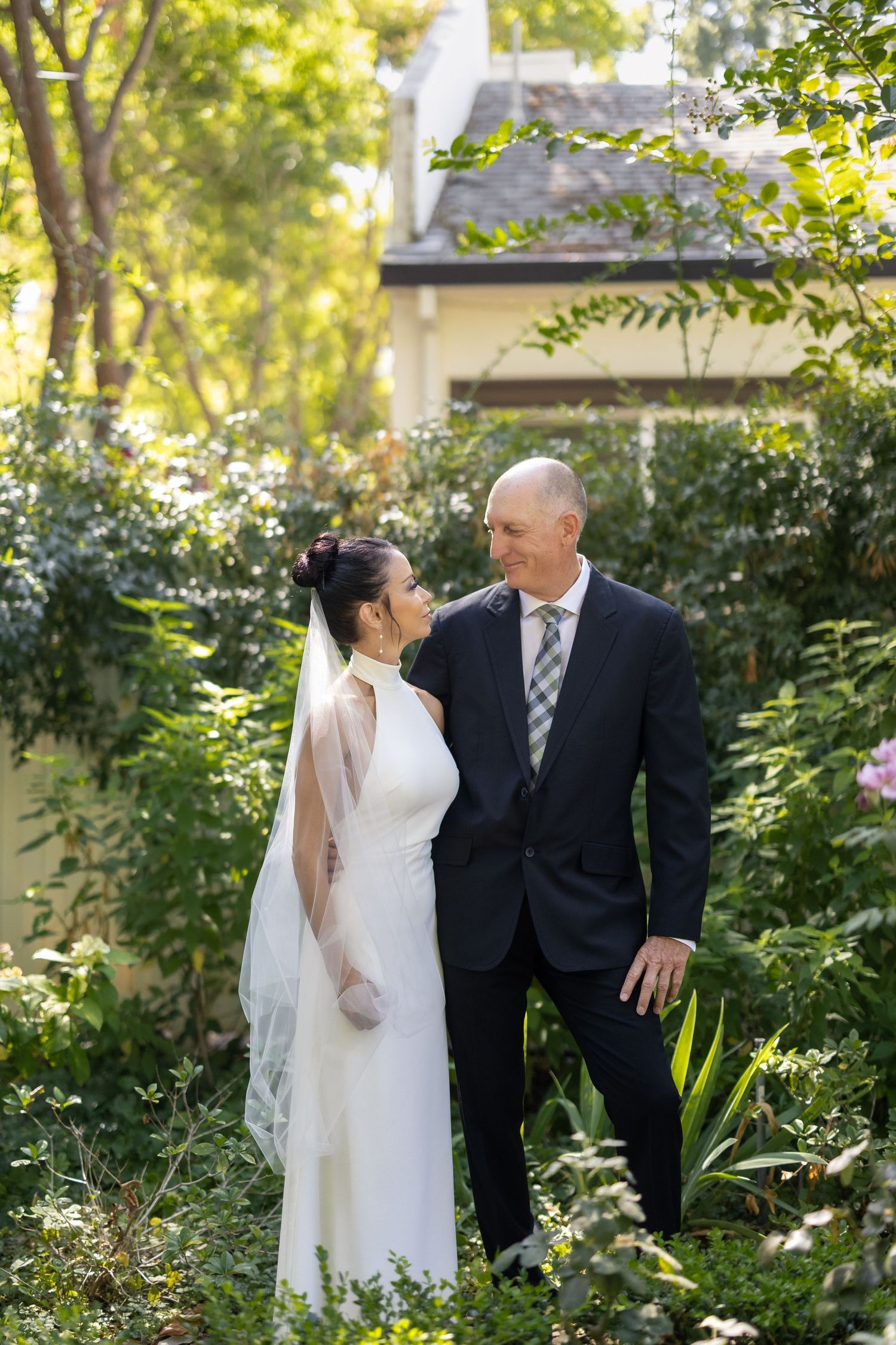 A couple shares intimate moments in a lush garden setting during their wedding photoshoot.