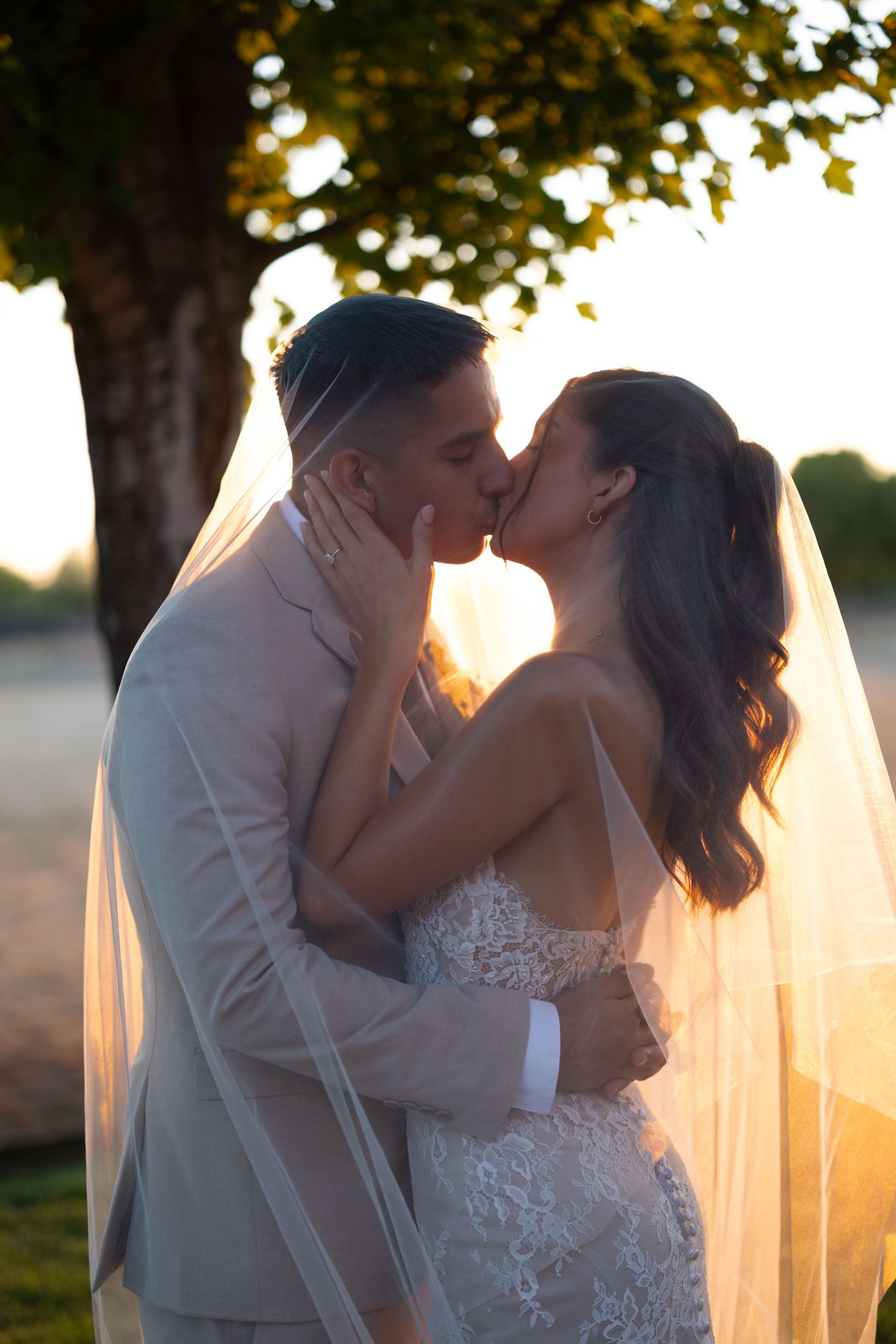 Romantic sunset wedding photos showing a couple sharing intimate kisses through a flowing veil.