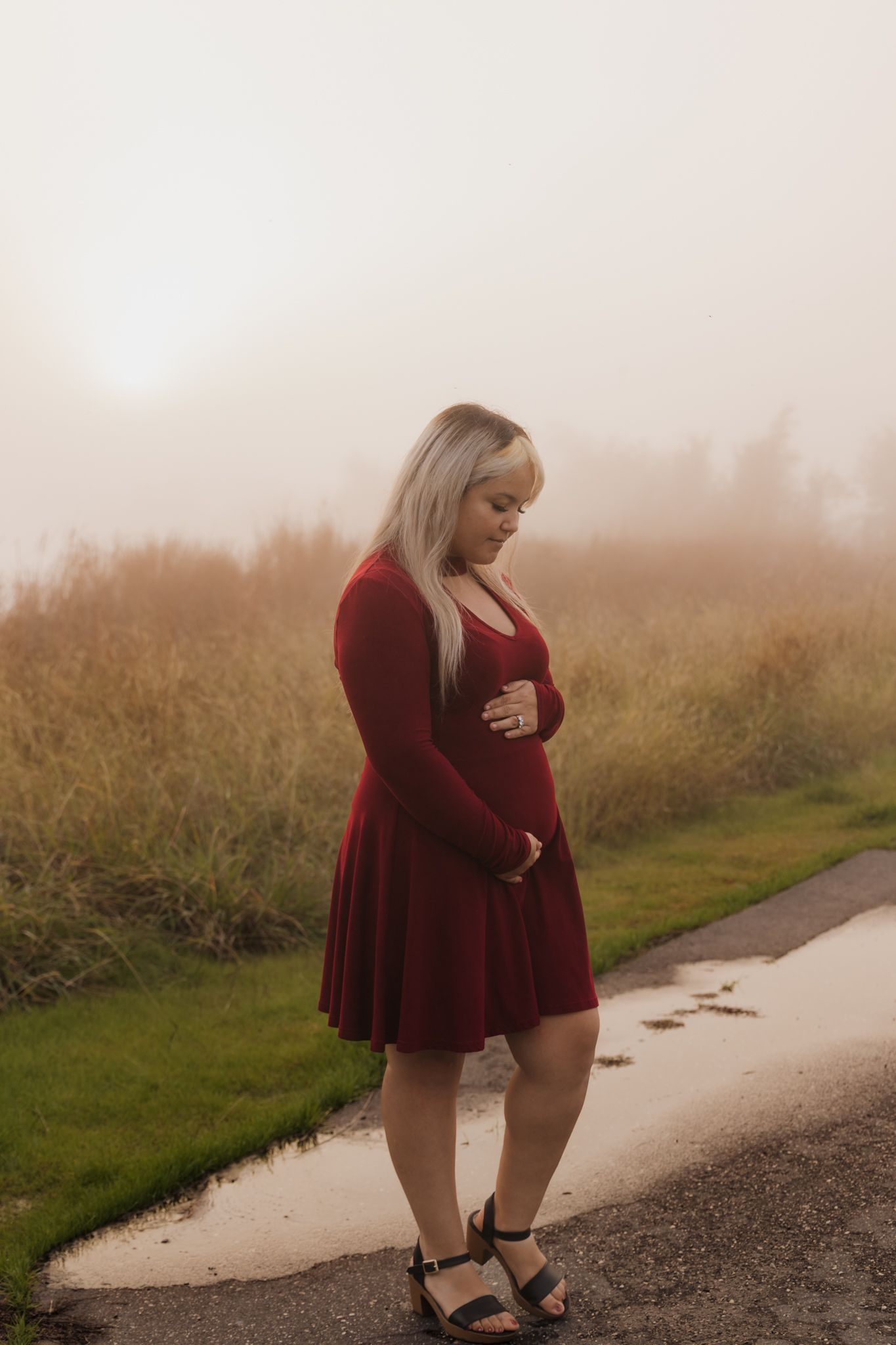A moody outdoor portrait session on a foggy path wearing a burgundy dress.