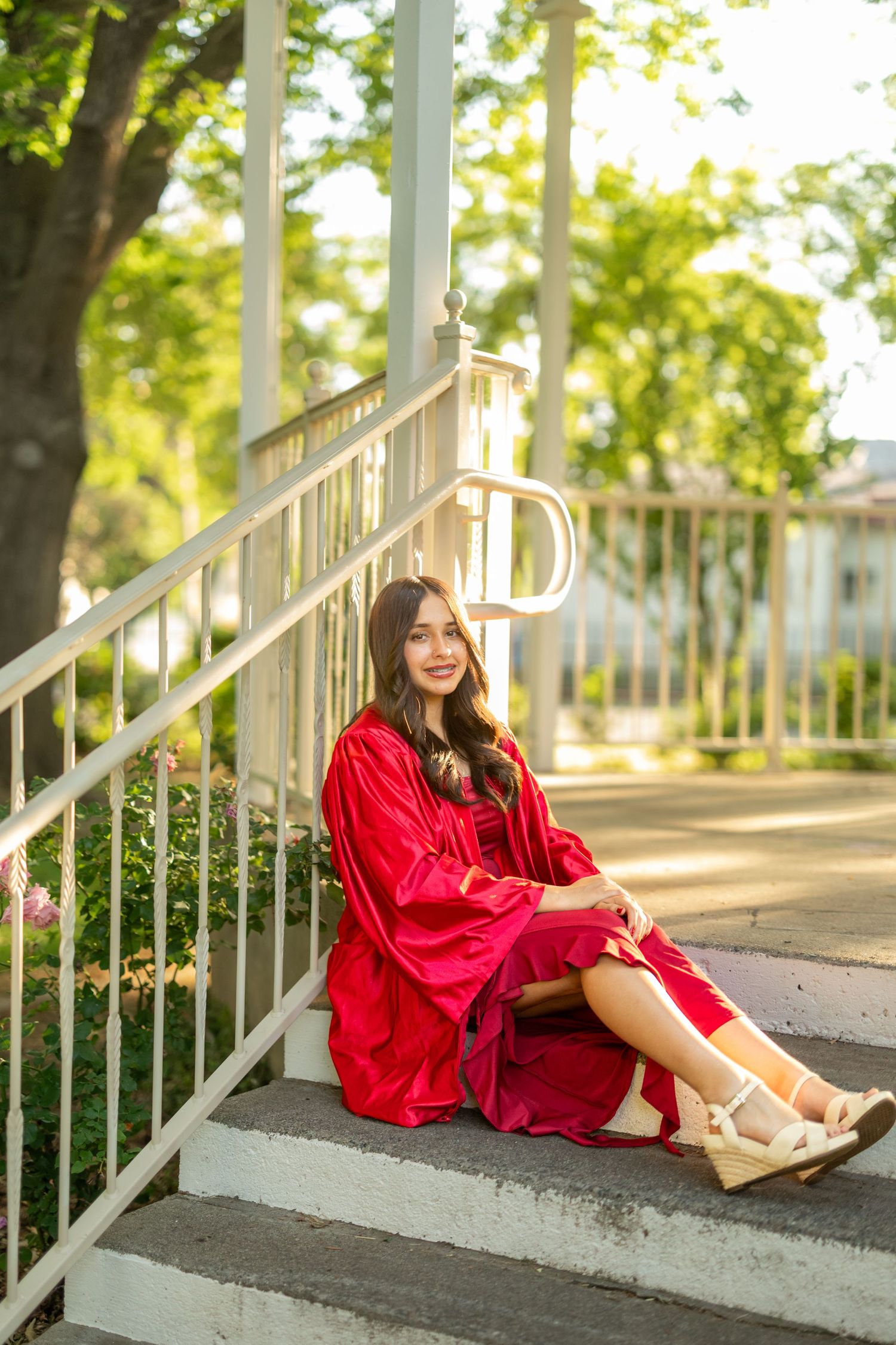 Series of casual poses on white stairs wearing a flowing red dress.