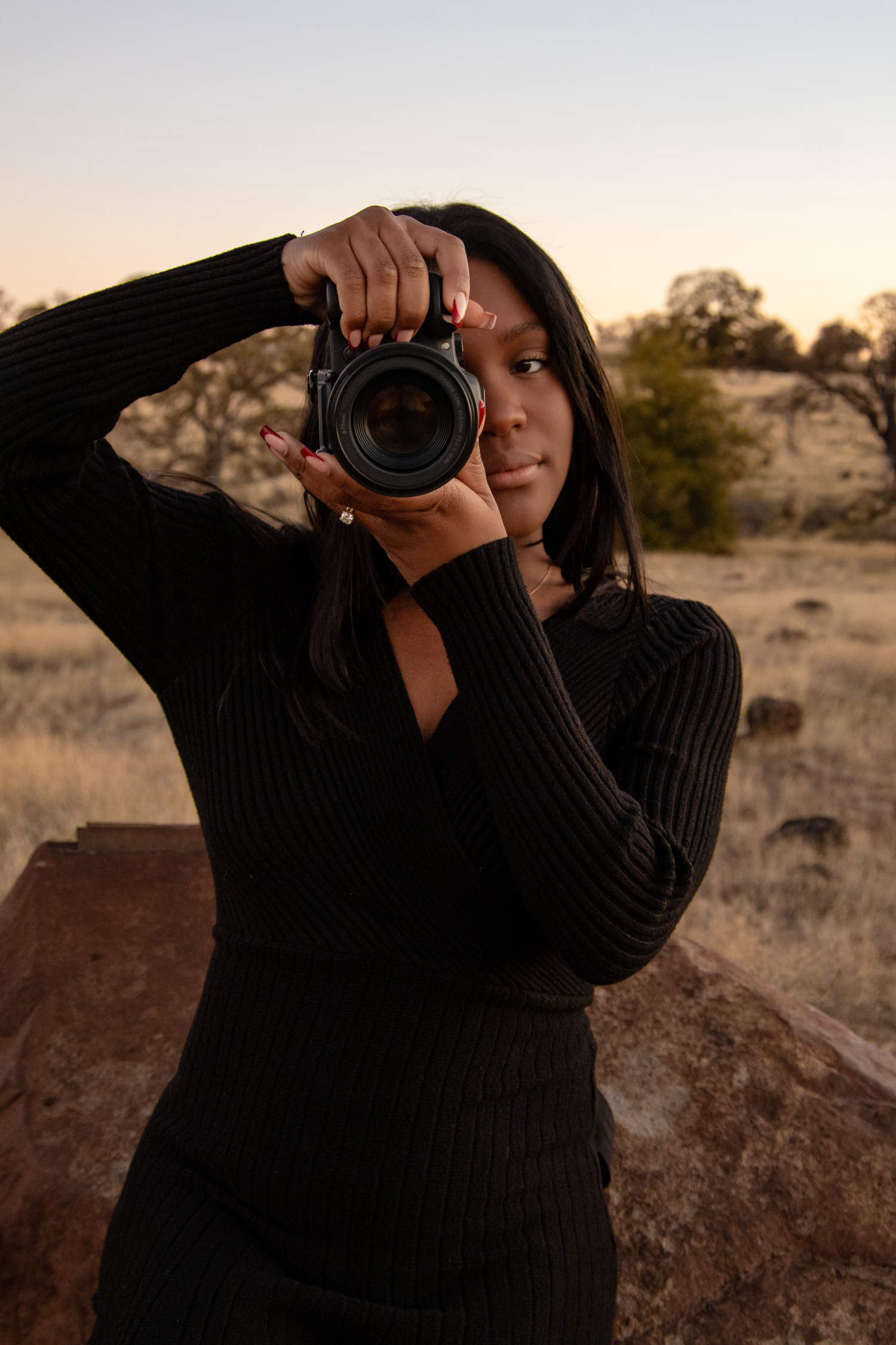 Photographer with camera poses against desert landscape at golden hour.