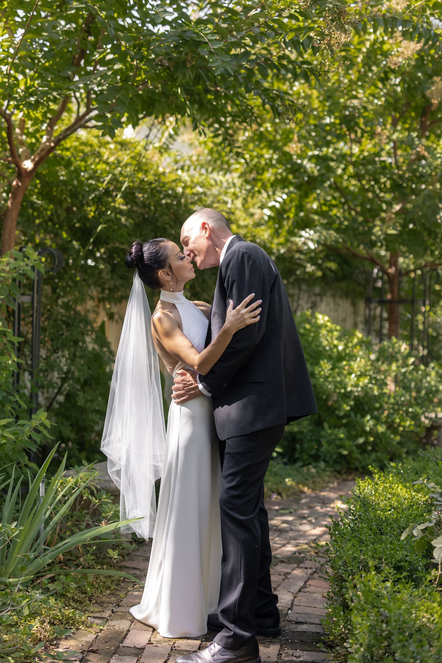 A romantic wedding photoshoot in a lush garden setting with a couple sharing a tender moment.