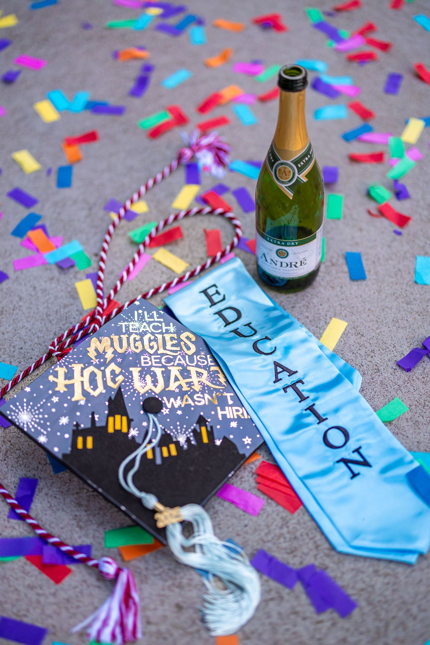 Graduation memorabilia with champagne bottle and confetti on grey background.