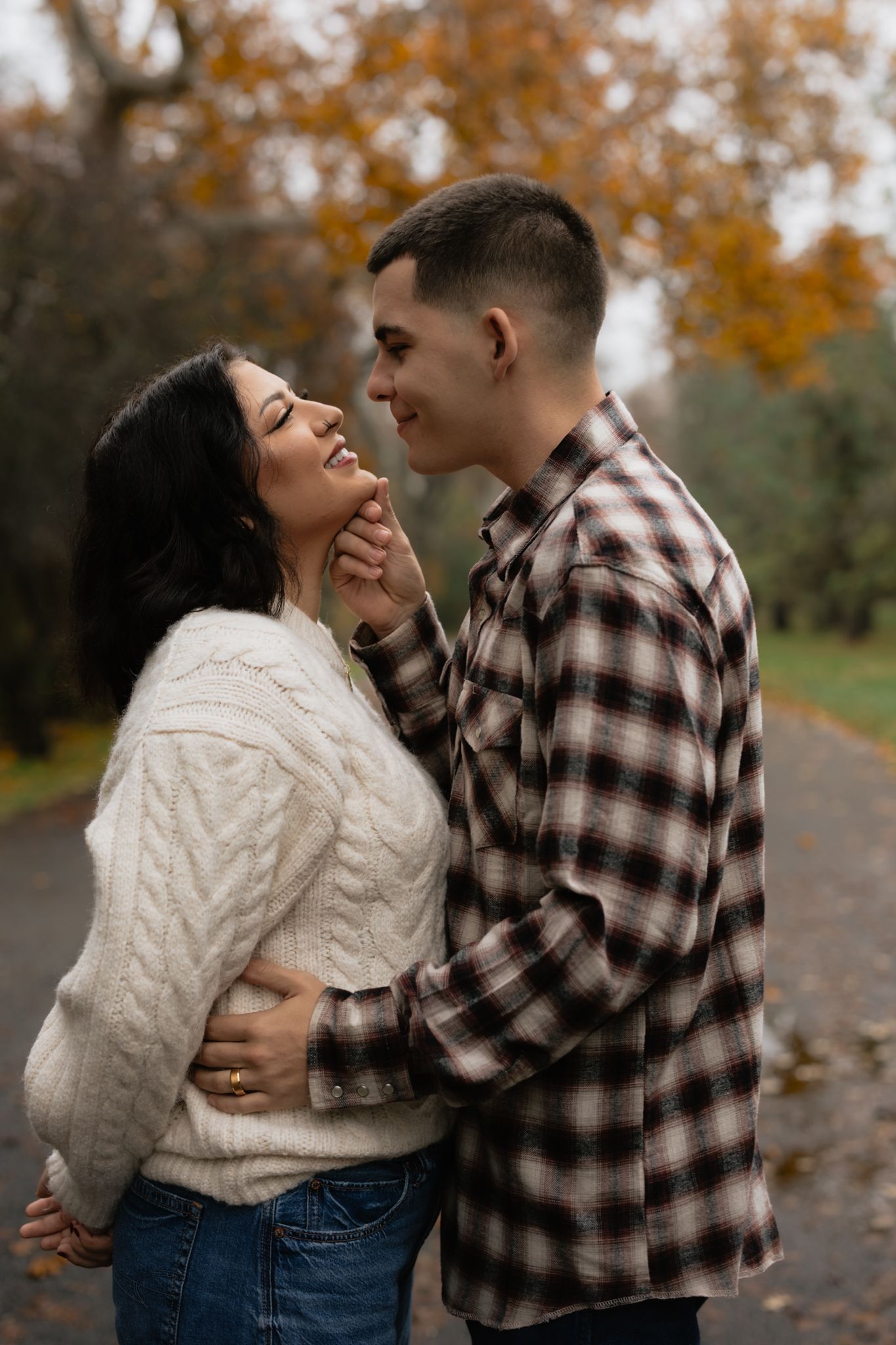 Couple in casual wear sharing intimate moment on autumn path.