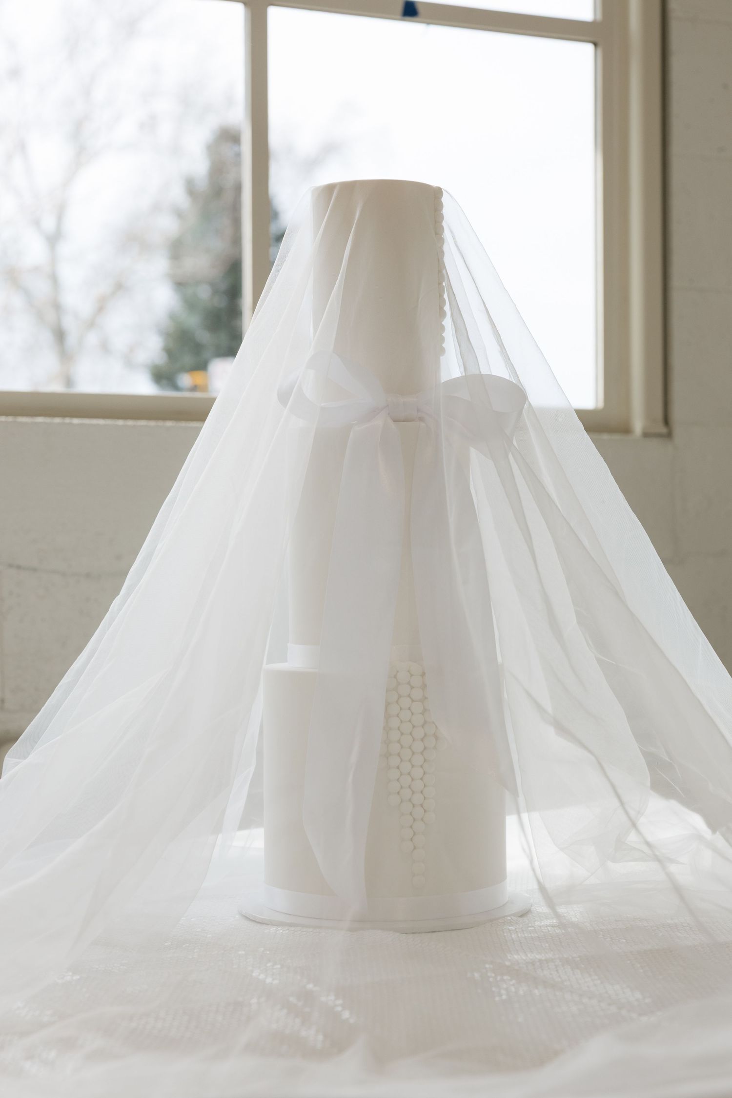 Close-up view of a white wedding dress train with delicate lace details and buttons arranged in a row.