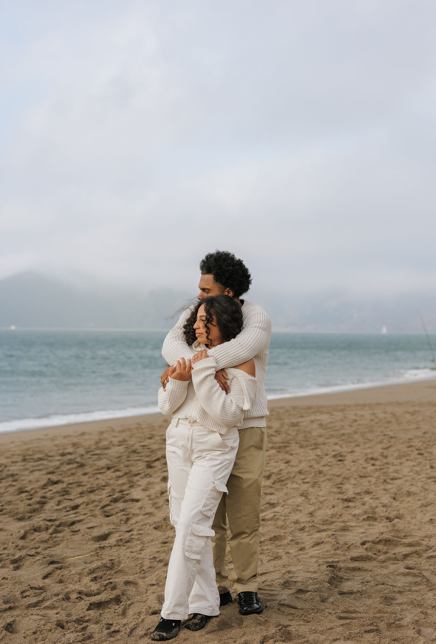 Candid moments captured on a sandy beach showing intimate poses in white clothing.