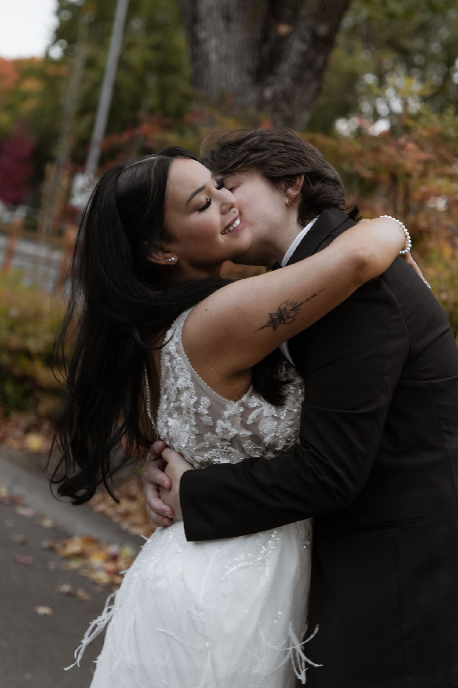 Intimate autumn wedding portraits captured on a leaf-covered pathway.