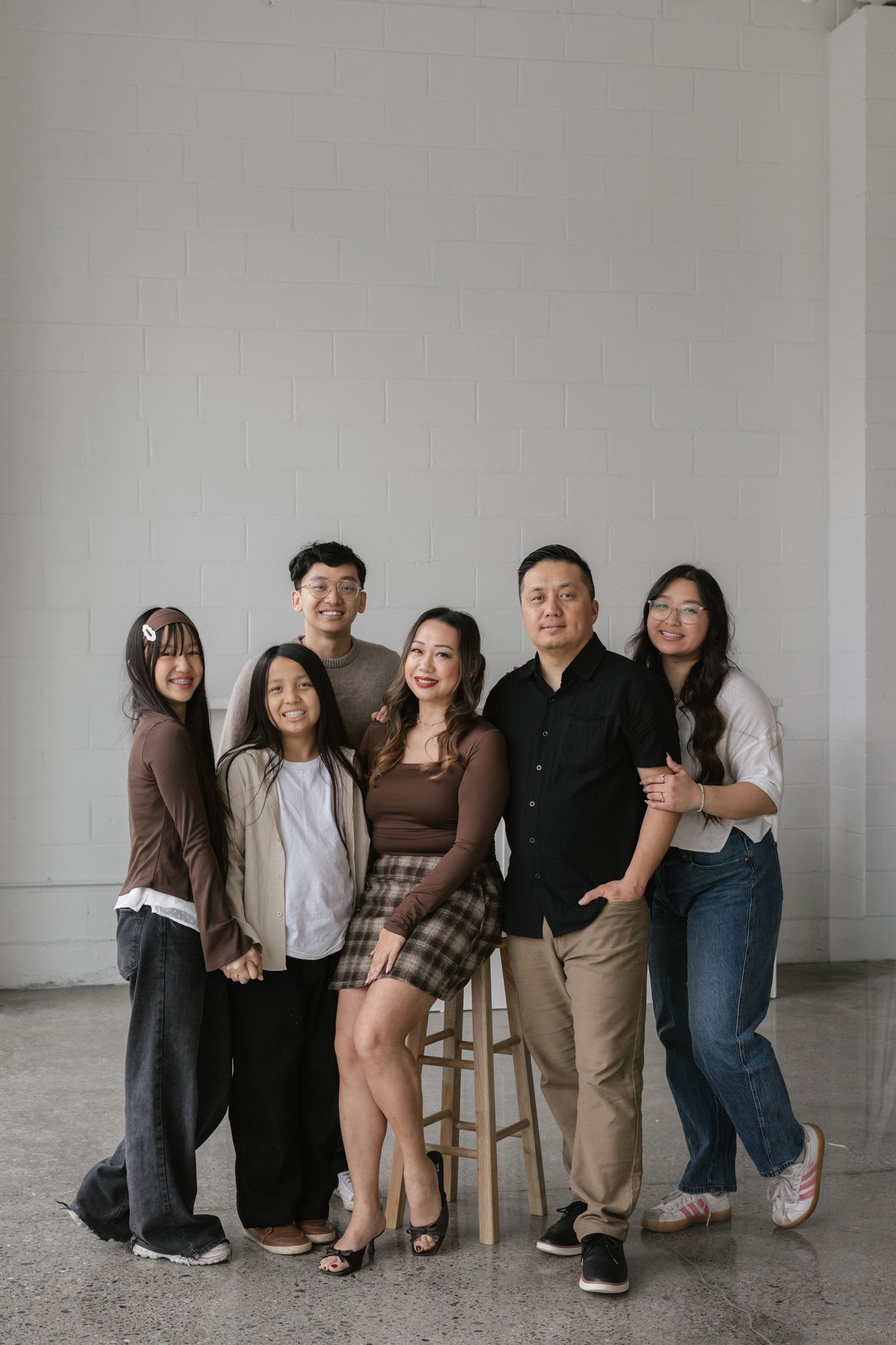 A group of people posing together in a minimalist studio setting against a white wall.