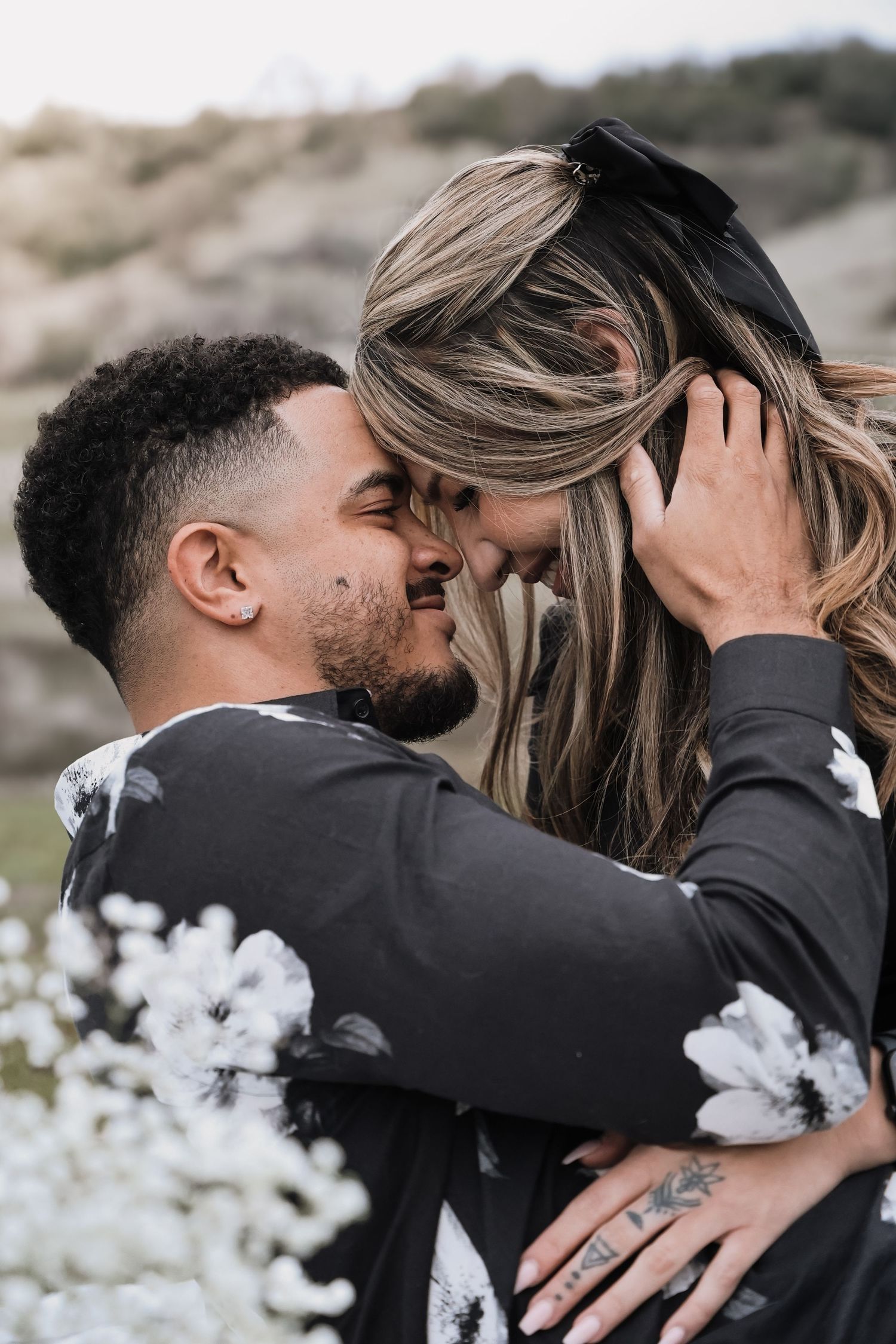 Intimate couple's photoshoot with black attire against white cotton field backdrop.