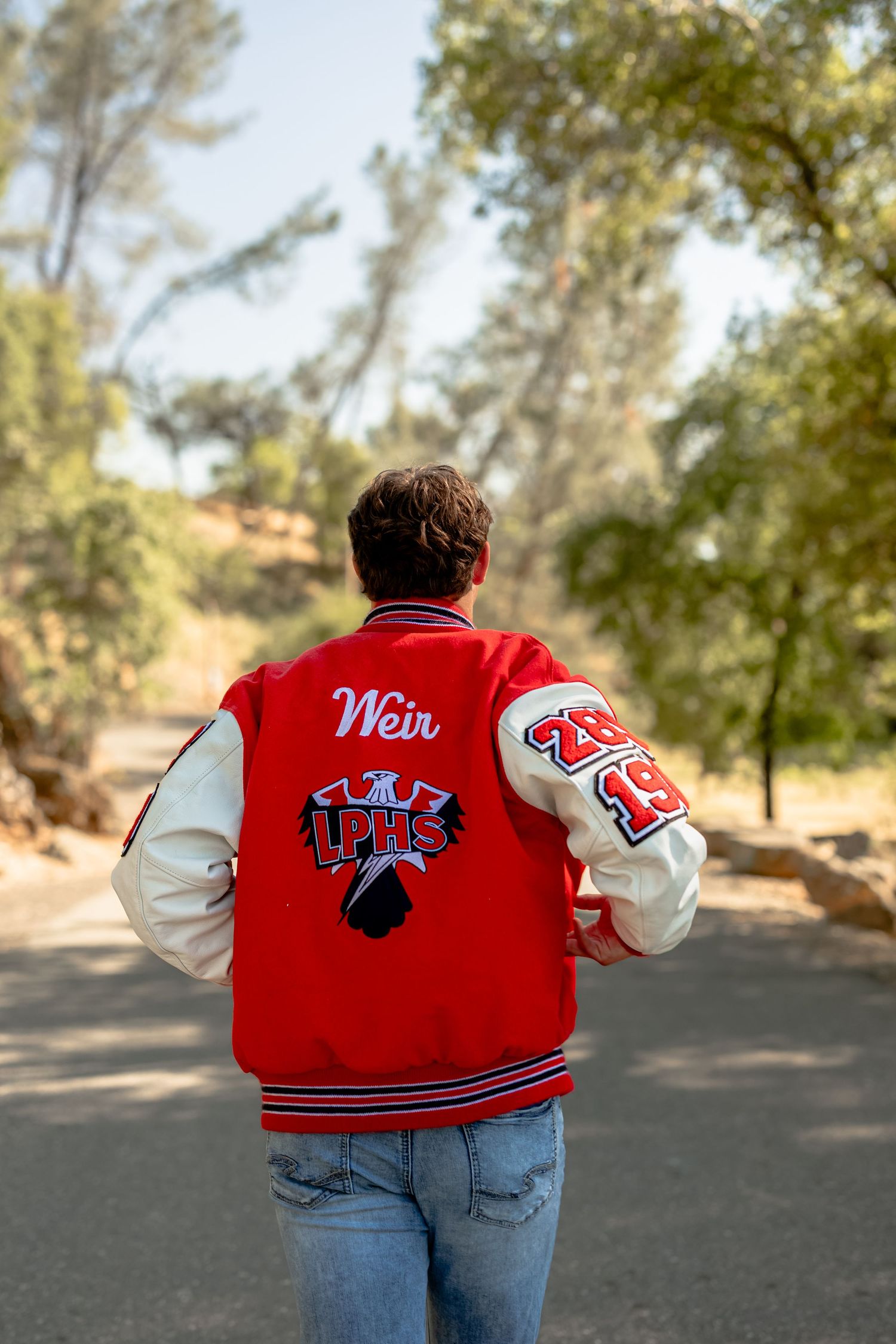 Red and white varsity letterman jacket shown from behind with school mascot details.