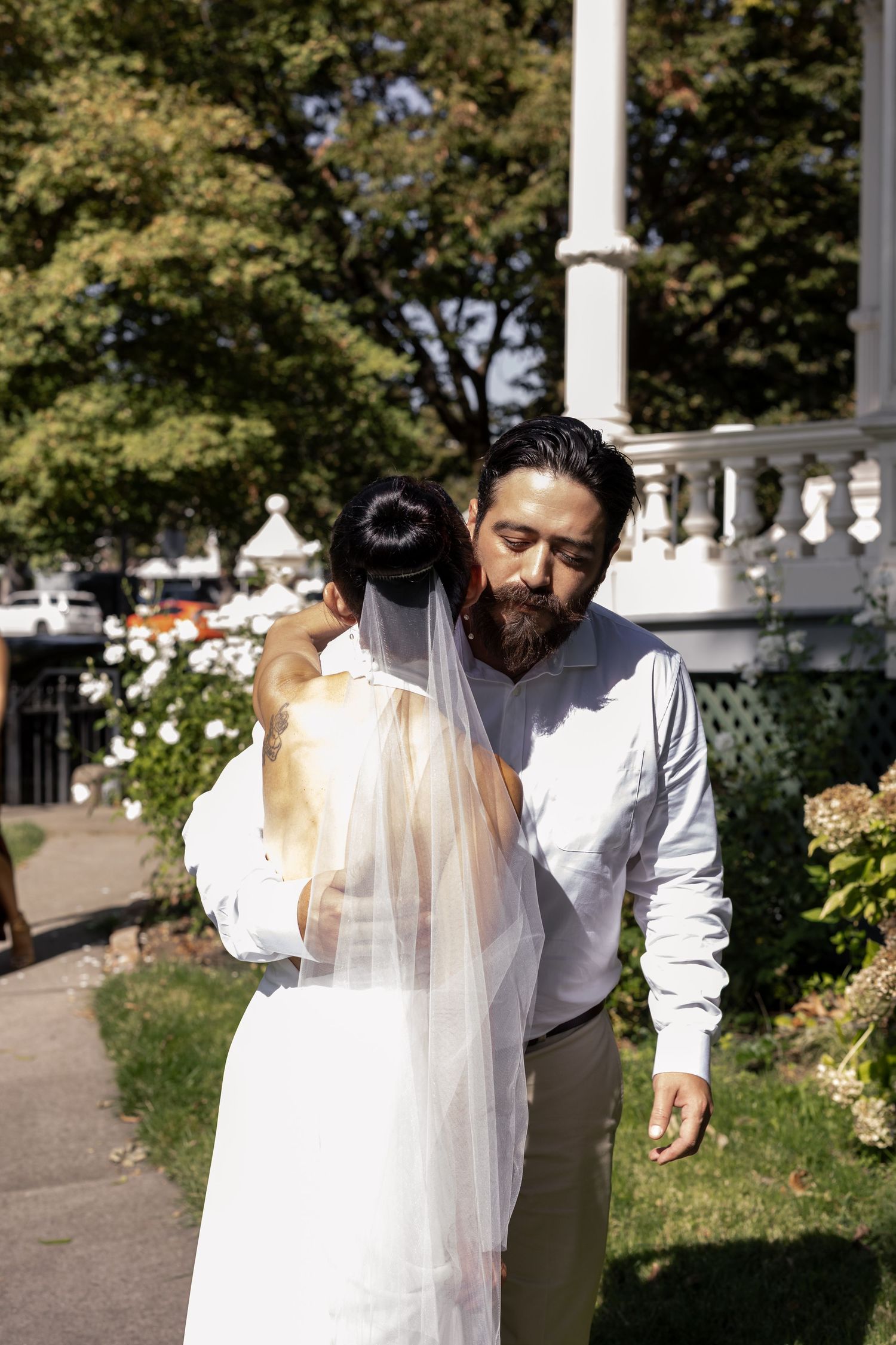 Wedding couple sharing intimate moments in a garden with white pillars and greenery.