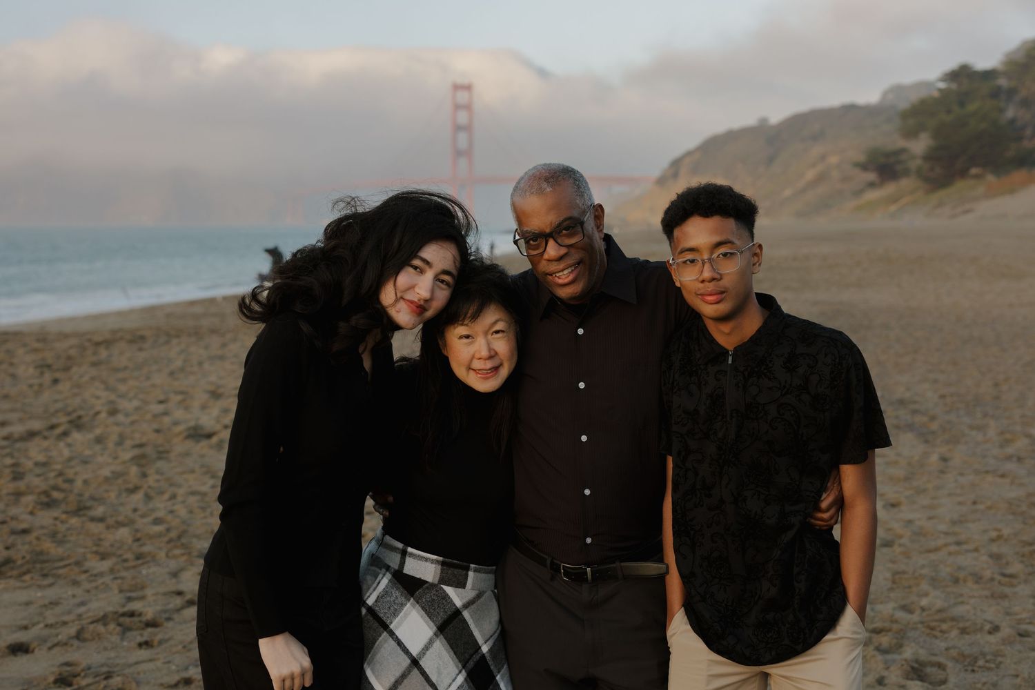 A group photo session at Baker Beach with the Golden Gate Bridge visible in the background.