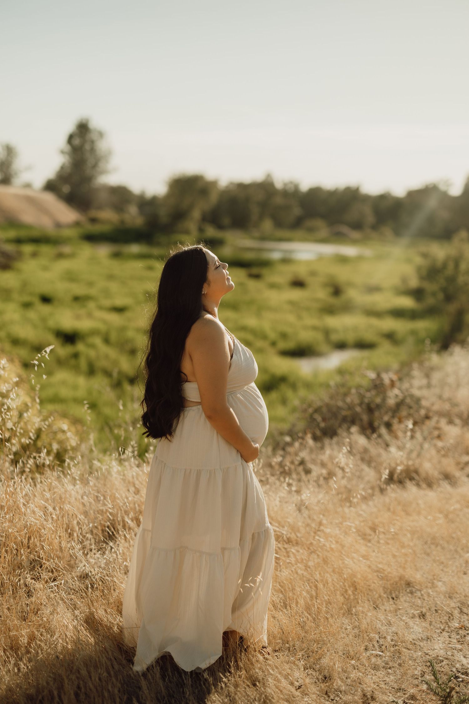 A person in white sits peacefully in a sunlit field of golden grass.