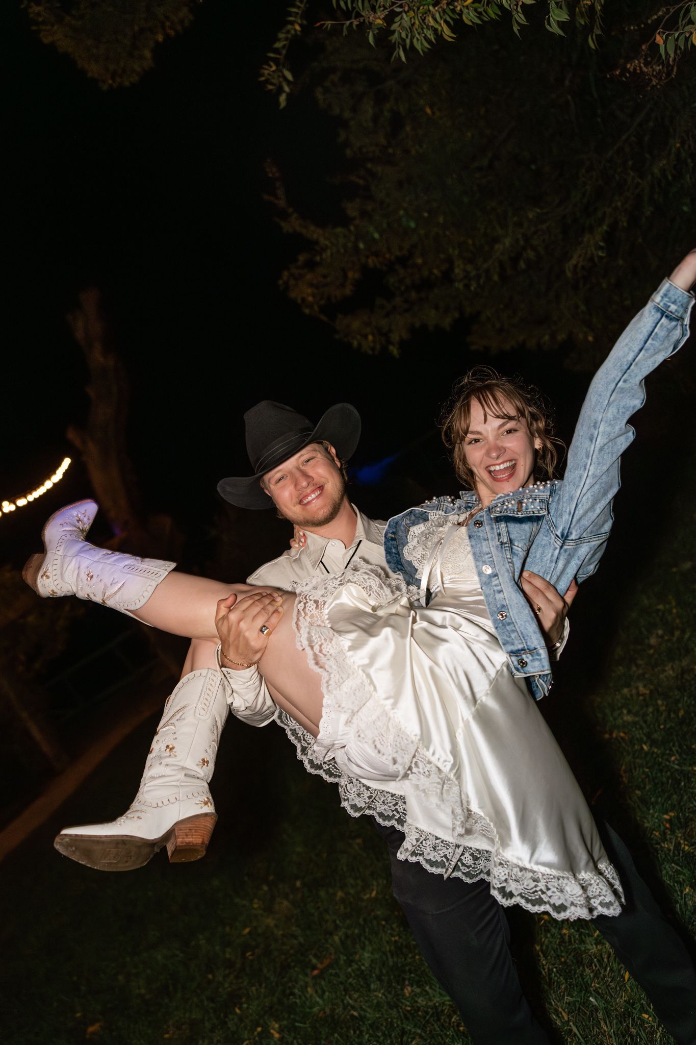 A couple performs a romantic dip dance move outdoors at night during what appears to be a wedding celebration.