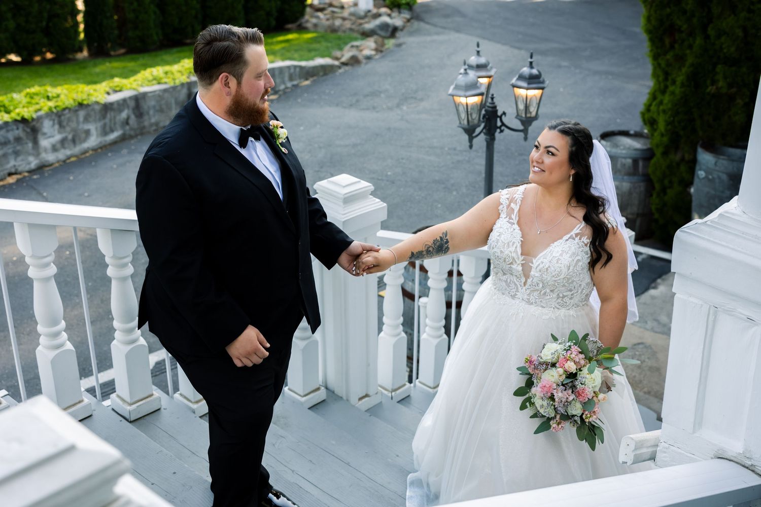 A wedding couple shares a moment on white stairs with decorative outdoor lanterns.