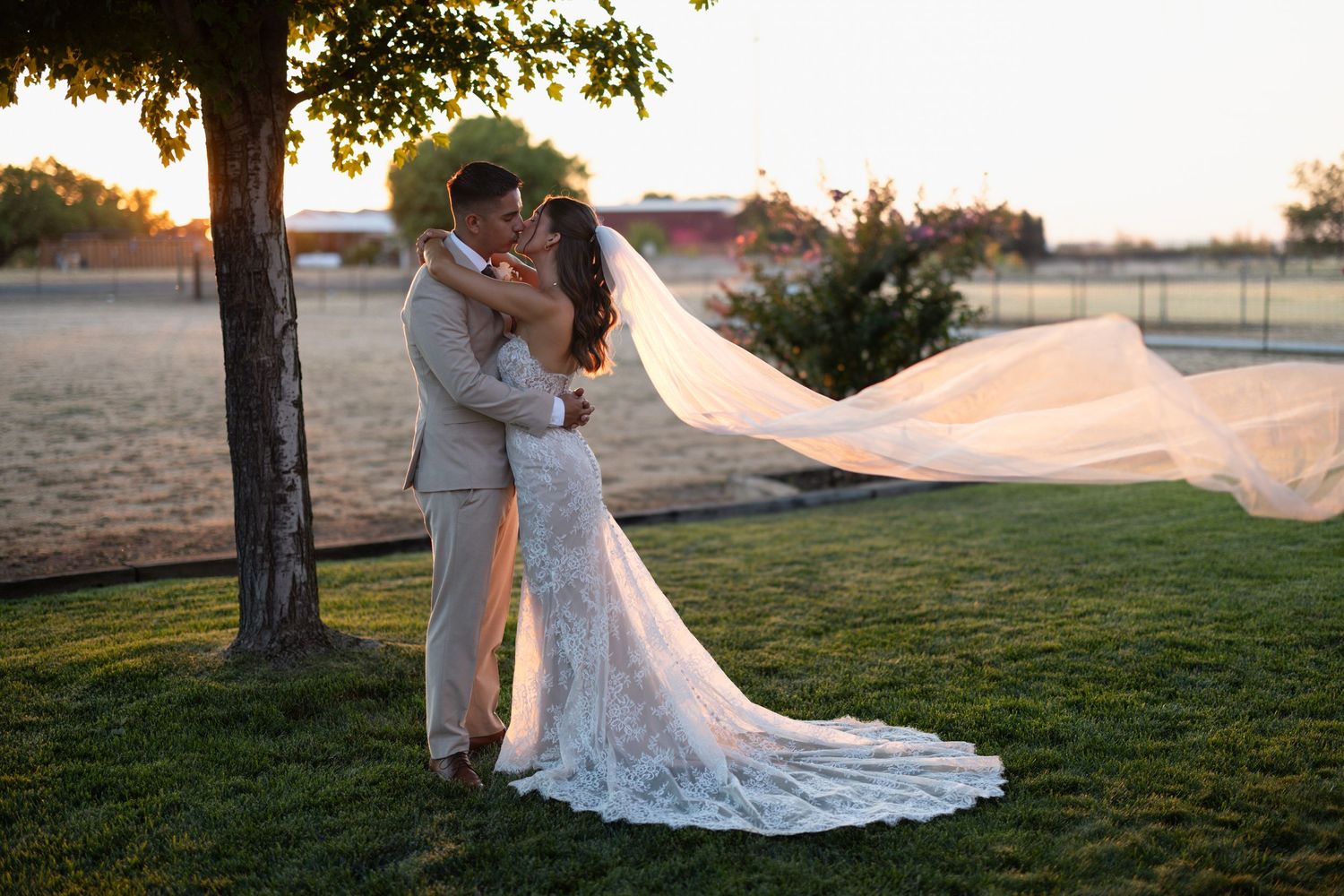 A romantic sunset wedding photo with the bride's veil flowing in the breeze.