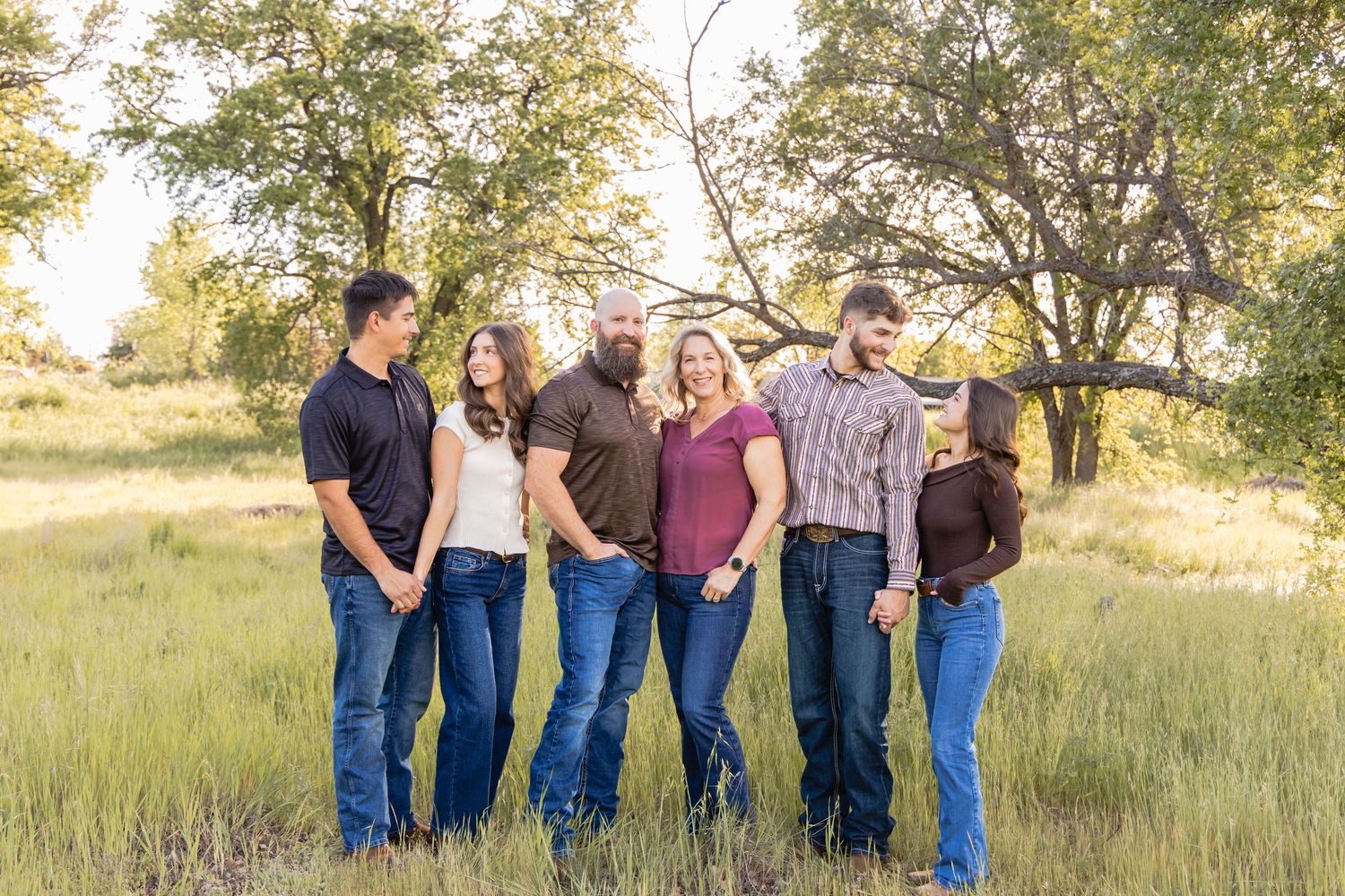 Extended family lined up outdoors in casual attire for group portraits.