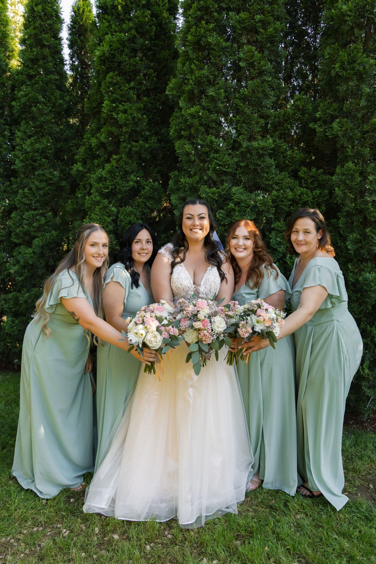 Bridal party in mint green dresses holding pink and white bouquets with the bride.